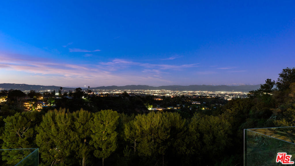 This luxurious property is a stunning Richard Landry-designed estate situated on a gated promontory on famous Mulholland Drive. The compound offers complete security & privacy with breathtaking 180 degree panoramic city views across 7+acres of land. The home's 4 bedrooms and 7 bathrooms, with state-of-the-art technology & superior materials used throughout the remodeled interior, features soaring ceilings, oversized rooms, a myriad of skylights. Retreat to your professional Dolby ATMOS screening room 13 comfort seater w/64 speakers & starry sky ceiling to watch movies after a busy day. Private hiking trails take you throughout the entire acreage, where you have a saltwater pool, jacuzzi, BBQ/diningarea & tennis/full basketball court overlooking the views. This unique property has an abundance of flat land, lush landscaping, its own koi pond & award-winning vineyard. The estate is a private playground for adults, kids & pets; the property has an automated kitchen window & bar/wine cellar; the vineyard Produces 3 delectable varietals; Viognier, Merlot, and Cabernet Sauvignon & the indoor atrium water features give this architectural master piece a luxurious resort-like feel; for the kids a treehouse, zipline, and swingset for outdoor entertainment & lets not forget the pets; an enclosed dog run and Cat-io. The home systems: a leak detection system, Crestron Control System with Lutron, Lutron controlled shades, video surveillance throughout the interior and exterior, 6 HVAC units; most rooms have their own zone; Swiss AirFiltration system ensures high-quality air throughout the home. The property features a 4-car garage, 2-car carport, and additional parking for 20+ cars, with an additional large back driveway. This estate is conveniently located close to Beverly Hills, the West Side & Valley locations, with easy access to the best private schools LA has to offer. This is a one of kind property not to be missed.