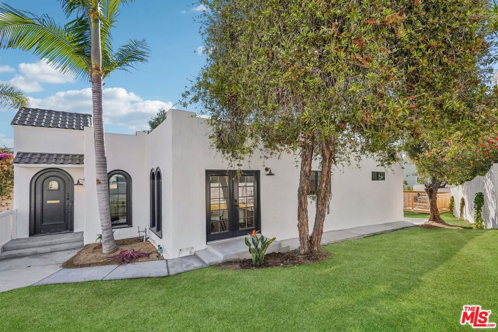 Welcome to 2353 Lucerne Ave, where timeless elegance meets modern luxury in this stunning Spanish Revival home that will capture your heart from the moment you arrive behind the charming white picket fence and discover your personal sanctuary a gorgeous retreat adorned with swaying palm trees, vibrant birds of paradise, and mature landscaping that creates an instant sense of tranquility. Enter through the welcoming foyer where beautiful marble tile floors gleam beneath soaring ceilings and an elegant chandelier sets the tone for the sophistication that flows throughout, as European oak floors guide you through graceful arched entryways into the completely renovated kitchen where your culinary dreams come alive with brand-new stainless steel appliances, a professional gas cooktop, and stunning tile work extending to the ceiling, all crowned by a custom-made range hood that serves as both functional art and conversation starter. The sun-drenched dining room showcases the home's original character with beautiful arched windows flooding the space with natural light while French doors open to the private side yard, creating seamless flow between kitchen, dining, and living areas that makes hosting a joy. Down the thoughtfully lit hallway, you'll discover a versatile first bedroom perfect as a guest suite or home office, plus a bathroom that's a work of art itself with unique tile floors and perfectly placed sconces creating spa-like ambiance, while convenient laundry placement keeps daily life effortless. The true showstopper awaits in the primary suite your personal oasis featuring peek-a-boo views, a palm tree framed perfectly outside your window, a generous walk-in closet, and the crown jewel master bathroom where luxury knows no bounds as you imagine starting each day with breathtaking views of the Santa Monica Mountains and Culver City from your soaking tub or refreshing in the double shower with double vanity convenience. Step outside to the back deck that beckons for morning coffee or evening gatherings surrounded by fruit trees that add both beauty and bounty to your daily life, while the detached garage offers endless possibilities as an art studio, motorcycle haven, or extra storage, complemented by easily accessible under-house storage and a newly redone front parking spot that seamlessly blends 1920s character with today's lifestyle needs. This isn't just a house it's your gateway to the California dream, where every detail has been carefully curated to create a living experience that's both luxurious and livable, so don't just imagine your perfect home come see it at 2353 Lucerne Ave and make this Spanish Revival masterpiece your own.