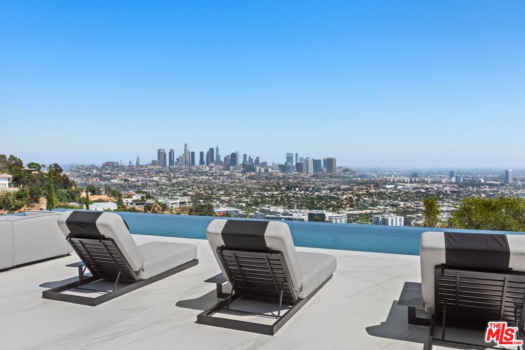 Perched in the most desirable area in the Hollywood Hills 1424 Tanager Way embodies modern luxury and architectural brilliance by renowned architect Paul McClean on arguably the best street in the Bird streets. This fully renovated residence boasts unparalleled views of the Los Angeles skyline, offering a breathtaking backdrop that captivates day and night. This extensive renovation left no detail untouched throughout the entirety of the property. As you approach the front entry you're greeted by a courtyard featuring an incredible double water feature wall with a fire feature centered between and LED lights scattered throughout, creating a striking ambiance that sets the tone upon arrival. Throughout the home you will find large format porcelain tile floors and venetian plaster walls/ceilings that add sophistication and texture. A standout feature of the living room is a majestic 100-year-old olive tree backlit by an LED wall, gracefully positioned behind a floor-to-ceiling glass frames. The properties on the left and right recently sold for $24 million and $25 million, underscoring the exceptional value of this location and view. Conveniently located near the world-famous Sunset Strip, residents enjoy easy access to vibrant nightlife, iconic music venues, and upscale dining. The home features a cutting-edge Control4 smart home system, seamlessly integrating lighting, climate control, security, and entertainment. Floor-to-ceiling Fleetwood doors and windows frame expansive views, while outdoor living spaces provide ideal settings for relaxation or entertainment. With luxurious finishes and a prime location, 1424 Tanager Way presents a rare opportunity to experience the ultimate Los Angeles lifestyle.