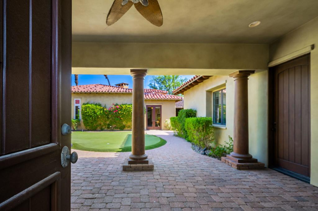An exceptional opportunity to lease a resort-style estate in the heart of La Quinta's exclusive Palms Golf Club. Nestled behind the gates of this boutique, low-density golf community, this sprawling compound spans over half an acre and is thoughtfully designed for luxurious desert living, effortless entertaining, and ultimate privacy. Surrounded by mountain vistas and lush, manicured grounds, the main residence offers approximately 5,000 square feet of open-concept living space, featuring 6 bedrooms and 5 bathrooms, including two expansive primary suites with spa-like en-suite baths and generous walk-in closets. The light-filled great room--with its dramatic ceilings, inviting fireplace, and seamless indoor-outdoor flow--connects to a chef's kitchen outfitted with slab granite countertops, stainless steel appliances, and an oversized island perfect for casual meals and lively gatherings. Guests are treated to their own private havens with three attached casitas--each offering either a kitchenette or a separate living room, en-suite or shared bathroom, and dedicated entrances from the central courtyard, allowing for comfort, flexibility, and total seclusion. The outdoor spaces are equally impressive. Enjoy resort-caliber amenities including a sparkling pool and elevated spa, misting system, putting green, lighted palapas for evening lounging, a firepit, and a fully-equipped outdoor kitchen with bar seating. Whether hosting a crowd or enjoying quiet evenings under the stars, the home is tailored for year-round enjoyment. Additional highlights include two separate two-car garages, a dedicated golf cart garage, and ample guest parking--combining function with thoughtful design. Located within The Palms Golf Club, where membership is optional, residents may access one of the desert's most revered private courses--co-designed by Masters Champion Fred Couples and renowned architect Brian Curley. The intimate clubhouse features three dining venues, a welcoming bar, a fully stocked golf shop, and a vibrant social calendar, making it a hub for both recreation and community. All just minutes from world-class golf, dining, shopping, and hiking, with quick access to Interstate 10 and the greater Coachella Valley. This one-of-a-kind property is the perfect desert escape--offering space, sophistication, and the rare combination of privacy and connection.