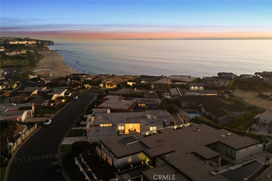 As waves break along Salt Creek Beach, evening lights shimmer after sunset and coastal bluffs rise to the summit of the towering Dana Point Headlands, all you have to do is relax and enjoy the views at this spacious single-level Hollywood Regency inspired contemporary home in Dana Point’s guard-gated Monarch Bay. Floor-to-ceiling windows and French doors welcome natural light and frame ocean views from most living areas. A formal entry with skylight leads to a living room that presents sit-down ocean and Headland views and a fireplace with custom marble surround while a formal dining room hosts a private patio, creating the ideal ambiance for elevated entertaining. Opening to two patios, the family room is bright, airy and warmed by a period-perfect wood-burning fireplace. A convenient pass-thru to the family room is just one of the amenities that awaits in the kitchen. Enjoy a nook with bay window, white cabinetry, stone countertops, marble backsplash, ample pantry storage, and top-tier appliances including a built-in refrigerator and an under-counter beverage refrigerator. Approximately 3,262 square feet, the three-bedroom, three- and one-half-bath design reveals understated sophistication with a soft white color palette that harmonizes with wood, stone and tile flooring, designer lighting fixtures, 11' ceilings and subdued millwork including crown molding and wall panels. A two-car garage and dual-zone air-conditioning are also featured. Manicured grounds extend nearly 11,305 square feet, offering room for future expansion of the home if desired. A patio wraps around the front of the residence, the side yard includes bocce ball and a putting green, and a private view courtyard displays an in-ground spa and generous patio space for entertaining. Monarch Bay, renowned as one of Southern California’s most sought-after oceanfront enclaves, offers residents access to the world-class amenities of its Monarch Bay Beach Club. Experience on-the-sand umbrella and beach-towel butler service, volleyball and oceanfront dining. A dog park, private tennis and pickleball courts, and beach fire pits are also included, and there are no HOA dues. Dana Point’s harbor, Laguna Beach, The Ritz-Carlton, and coastal trails and premium golf are moments from home.