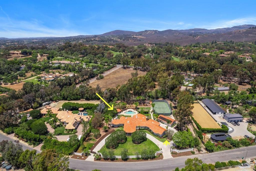 Experience the pinnacle of Southern California living at this rare and prestigious gated estate, spanning over 2 acres in the highly coveted community of Rancho Santa Fe! Set in a serene, park-like setting, this exquisitely reimagined single-level Mediterranean residence seamlessly blends timeless architecture with modern luxury. From the moment you enter through the gate, a grand circular driveway leads to a rare porte-cochère entry. Beyond the gates, this magnificent home unfolds into a luxurious haven thoughtfully curated for both intimate living and large-scale entertaining. The resort-style amenities feature a lighted tennis court with basketball hoop, a swimming pool and spa, charming playhouse, covered gazebo with outdoor fireplace, and a fully detached guest house offering a full kitchen and living room—ideal for extended stays or visiting guests. Inside, refined finishes and architectural details abound. Handcrafted terra cotta floors, solid walnut hardwood, elegant arched passageways, crown molding, LED lighting, solid wood doors, and premium hardware throughout. The entertainer’s wet bar, nestled between the formal living and great room, features a wine cooler, built-in refrigeration, and sleek storage. The gourmet chef’s kitchen is a masterpiece, appointed with solid walnut inset cabinetry, sleek quartz countertops, a top-of-the-line Wolf range, hood, and Sub-Zero refrigerator. The adjacent breakfast nook, surrounded by large windows and an in-wall fireplace, is bathed in natural light. A richly paneled office with custom built-ins provides a refined space for work or study. The luxurious primary suite is a private sanctuary, featuring vaulted ceilings, a dual-sided fireplace, and a spacious sitting area. The spa-inspired bath boasts Carrera marble countertops, dual vanities, a walk-in dry sauna, and expansive his-and-hers walk-in closets. Each of the 3 additional bedrooms includes a private en-suite bath and walk-in closets. The meticulously landscaped grounds are fully usable and include a separate service driveway. Zoned for horses and surrounded by equestrian properties, this estate offers endless possibilities—from equestrian facilities to personalized luxury expansions. Located within the award-winning Rancho Santa Fe School District and just minutes from the historic village, this property offers the best of luxury living, privacy, and community. An exceptional lifestyle awaits, schedule a tour today!
