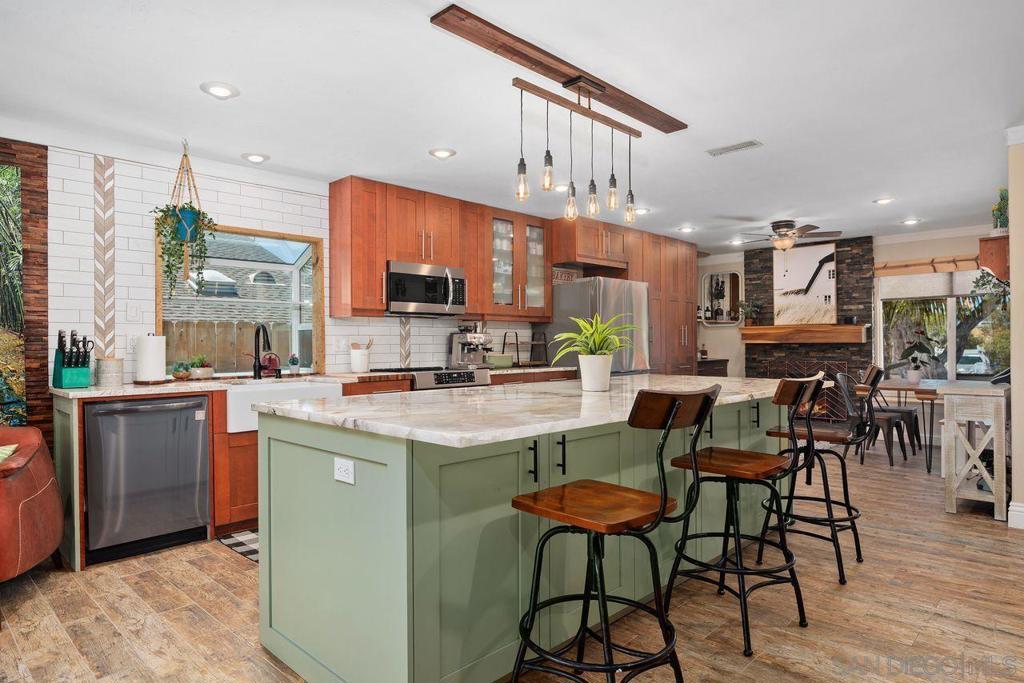 This beautifully reimagined Cardiff home blends artisan craftsmanship with thoughtful upgrades and stylish design. Featuring an open great room concept, the layout flows seamlessly from the office nook and dining area, through the iconic kitchen to the family room, and into the yard beyond. At the heart of the home, the kitchen impresses with its dramatic 9-foot Alpinus Super Crystal Granite island, beverage fridge, and solid wood cabinetry. It’s outfitted with an induction range and air fryer oven, a new refrigerator with a convertible third compartment, and elegant finishes throughout, including striking backsplash and black hardware. A textured wood accent wall adds warmth and character to the inviting family room, and a doggie door adds convenience and easy outdoor access for your furry friends. Step outside to your fully fenced yard with lush turf, a covered patio, and park-like views to the east. Designed for entertaining and year-round indoor/outdoor enjoyment, the backyard features a hot tub, a crystal fire pit with a dedicated gas line, a party cabana, and beautiful redwood fencing for enclosure, privacy, and aesthetics! The serene primary suite offers sliding doors to the backyard, dual mirrored closets, and a gorgeously remodeled bathroom with a walk-in shower, bifold barn doors, and stunning ceramic tile wall paneling. A truly extraordinary home! (see supplement for more!) Other highlights include a retaining wall expanding the north side yard, dual attic storage spaces with board flooring, and a spacious 2-car garage with floating vinyl floors. Additional features: • Ceramic wood-look tile and carpet tiles in bedrooms • Crown molding, ceiling fans in all bedrooms and two in the great room • HVAC and water heater both less than 4 years old • 3-car driveway with space for a 21’ RV All this, in a fantastic Cardiff location—just a mile or under from Cardiff and Ada Harris Elementary, Encinitas Community Park, the beach, the Cardiff Rail Trail, Seaside Market, Pipes Café, and more!