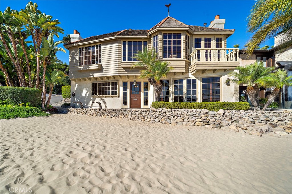 COASTAL EUROPEAN CHATEAUX IN HISTORIC CHINA COVE. An extraordinary opportunity to lease one of only a few beachfront homes in the ultra-exclusive enclave of China Cove, Corona del Mar. This custom-built Coastal European-inspired residence offers an unparalleled front-row experience with sweeping views of Newport Harbor, Ocean, and golden sunsets from nearly every room. Thoughtfully designed with bespoke craftsmanship, this timeless home features rich wood beams, intricate ceiling treatments, built-ins, custom moldings, hardwood floors, custom shutters, and brass fixtures throughout. Ocean breezes drift through multiple sets of French doors, enhancing the effortless indoor-outdoor coastal lifestyle. The main level’s great room layout blends kitchen, dining, and living spaces, all opening directly to the beachfront deck—ideal for relaxed gatherings and morning coffee by the sea. Anchored by a statement fireplace, the inviting living room flows into a kitchen that marries Old World charm with modern convenience. Features include built-in appliances, gas cooking range, custom copper hood, and artisan tilework. The elevated primary suite is a private retreat, complete with coved and beamed ceilings, a marble fireplace with hand-carved mantle, and its own balcony with panoramic ocean and harbor views. The luxurious ensuite bath is clad in handcrafted azure tile and features a deep soaking tub and dual-sink vanity. A rock-grotto spa nestled in the rear courtyard offers a secluded spot to unwind, with direct access to a guest bath. The home also includes an enclosed one-car garage and parking for two more vehicles on the custom paver driveway. Manicured landscaping with timed irrigation ensures low-maintenance beauty. Now Leasing | Shown by Private Appointment