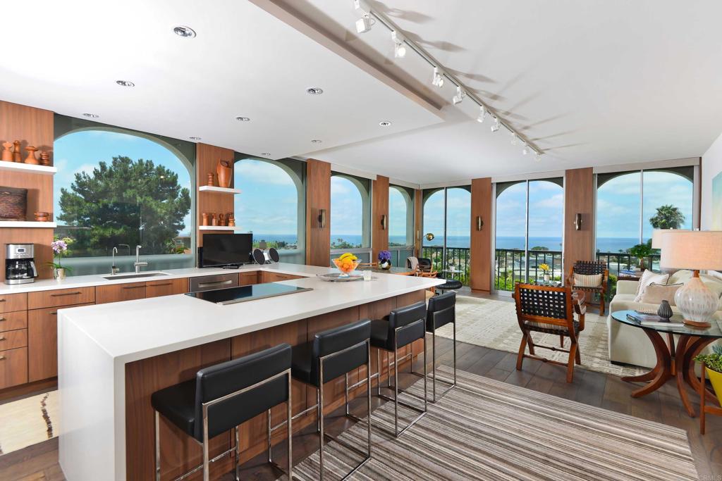 Exquisitely Remodeled Ocean-View Condo with Designer Touches. Enjoy effortless luxury in this beautifully renovated, single-level condo featuring panoramic ocean and golf course views from the quiet cul-de-sac Seville building. Thoughtfully curated by a designer, the residence blends mid-century original vintage furniture with modern upgrades, including all original artwork throughout. The expansive great room showcases floor-to-ceiling windows on two sides, stunning wood floors, and a king sleeper sofa for guests. The open-concept kitchen boasts Bosch appliances, a drinking water purification system, and stylish finishes that elevate both form and function. The bedroom includes remote-controlled blackout shades, ensuring restful sleep with complete privacy. The spa-inspired bathroom features a view shower with high-end finishes. Additional amenities: * Two TV's * All utilities included (internet, cable TV, water, electricity) * Bi-monthly housekeeping service * 24-hour doorman and onsite maintenance * Heated pool, spa, and well-equipped exercise room * Private, assigned covered parking space * Laundry in basement area * Located near La Jolla’s best beaches, Village shops, restaurants, museums, parks, and the Sunday Farmers Market.