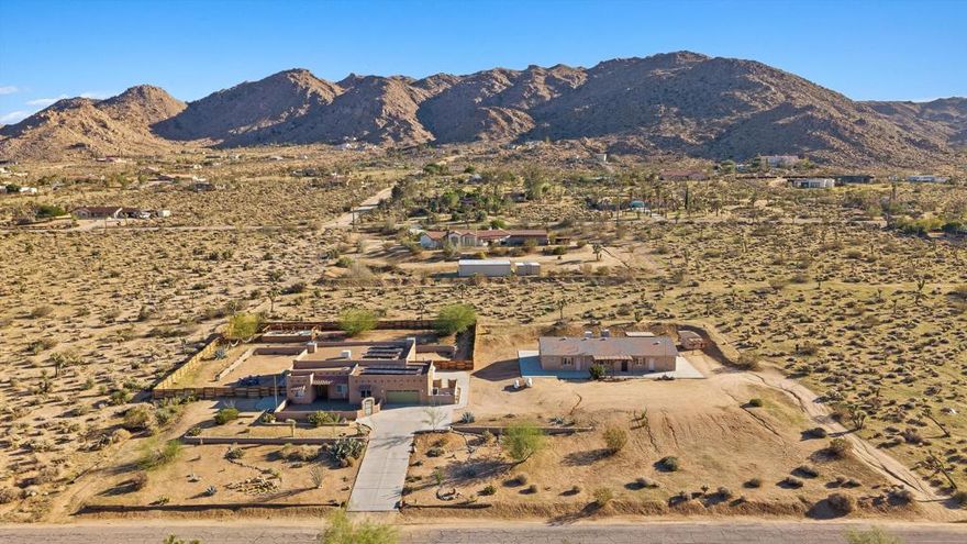 Rare opportunity in South Joshua Tree: Two homes, totaling 5 beds and 4 baths, on one 2.3-acre lot in a great location. With so many potential future uses for a new owner, this property offers double income potential, or the flexibility to live in one home while renting the other, or keep both for family and your guests. Zoned Residential 2, these are two separate full residences, not just a main home with a guest house - making this a truly unique opportunity. House A is a custom Santa Fe-style build with 3 bedrooms + den, 2 bathrooms, and a spacious open. Enter the home via the large, private front deck and enter to find 10' ceilings, an updated kitchen, large great room, and an expansive primary suite, complete with a stone pellet stove, walk-in closet, and en-suite bath with jetted tub and separate shower. The home also has an individual laundry room and garage (which is currently used as a game room). The expansive yard features an elevated deck with cowboy tub, jacuzzi, and plenty of space for entertaining and stargazing. House B offers 2 bedrooms and 2 bathrooms, full kitchen with stainless appliances, its own laundry, and another attached garage (also currently set up as a game room). Outside you'll find another jacuzzi and plenty of space to enjoy. Other highlights include: OWNED solar on the main house, outdoor fire pit and sweeping valley and mountain views.
