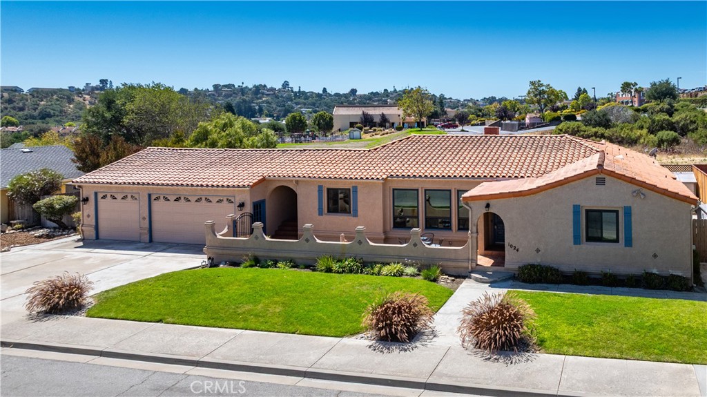 Welcome to 1024 Robin Circle, a beautifully remodeled 3-bedroom, 2.5-bath Spanish-inspired ranch style home in one of East Arroyo Grande’s most desirable neighborhoods. With its timeless red-tile roof, arched entryways, and charming front courtyard with fountain, this home blends Mediterranean charm with modern comforts. Step inside to find open-beamed ceilings, hand-scraped hickory hardwood floors throughout, and a unique two-way fireplace that warms both the living and family rooms. The sunlit dining room opens through French doors to a Saltillo-tiled breezeway, connecting seamlessly to the oversized 3-car garage with an 800 sq ft workshop. The kitchen is both stylish and functional, featuring stainless steel appliances, tile counters, a breakfast bar, recessed lighting, and a built-in desk. Just off the kitchen, the laundry room includes built-in cabinets and direct access to the backyard patio. The sunken family room offers a wet bar — perfect for entertaining — while arched doorways and architectural details enhance the home’s Spanish character. Two bedrooms enjoy adjacent bathrooms for comfort and privacy. Outdoors, the easy-care landscaping with drip irrigation and sprinklers, plus two storage sheds, make maintenance simple. The location is unbeatable: just minutes from the Village of Arroyo Grande with its local shops, restaurants, and farmers markets, while also close to Lopez Lake, top-rated schools, wineries, and the Central Coast’s pristine beaches like Pismo and Shell. Trails, parks, and playgrounds are just around the corner, giving you endless options to enjoy the Arroyo Grande lifestyle.