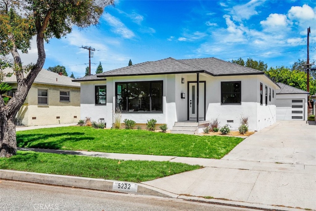 Welcome to 5232 Adenmoor Avenue, a fully renovated single-story home in Lakewood offering bright modern interiors, a functional open layout, and stylish upgrades throughout—wrapped in a clean white exterior with sleek black trim for instant curb appeal.
A paved driveway runs along the right side of the home, leading to a detached garage and gated backyard. The home’s front elevation is striking with large black-trimmed windows and matching accents along the door and posts, creating a balanced, modern look.
Inside, you’re welcomed by a light-filled open concept living and dining area, where recessed lighting, soft-toned wood flooring, and white walls create a fresh, airy atmosphere. A large picture window at the front fills the living room with natural light, while the adjacent dining space seamlessly connects the layout.
Off the dining area, the updated kitchen features a sleek galley-style design with waterfall marble countertops, coordinating marble backsplash, and black fixtures that echo the trim details seen throughout. White cabinetry with matte black hardware adds a clean, high-contrast finish. At the end of the kitchen is a spacious laundry room with geometric tiled floors, built-in storage, and access to a stylish half bath with wood accents. Just beyond, a bonus living area spans the back of the home with a full wall of windows and sliding glass doors overlooking the backyard. A modern black and marble fireplace anchors the room, adding both warmth and a contemporary touch.
Off the main living area, a hallway leads to two well-sized bedrooms and two full bathrooms. One bedroom features its own en-suite bath with a glass walk-in shower, marble-style walls, and a full closet. The secondary bedroom sits next to a bright hall bath with crisp white rectangular tile, black fixtures, and updated finishes throughout.
The backyard offers generous space for entertaining or outdoor projects, with direct access to the detached garage via a side door. A white side fence separates the yard from the long paved driveway, offering flexibility, privacy, and easy access to the garage entrance.
5232 Adenmoor Ave is a turnkey, design-forward home in a sought-after Lakewood neighborhood—combining modern style with single-level ease and indoor-outdoor versatility.