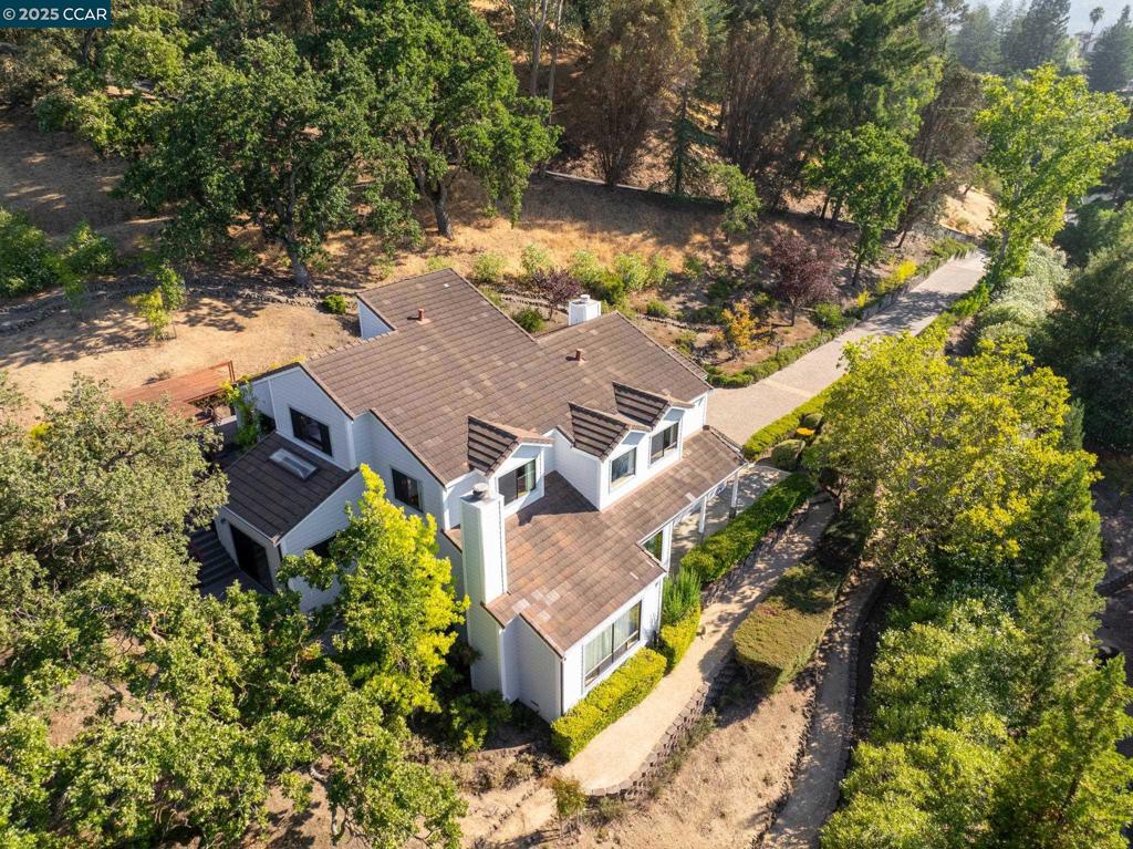 Perched on over an acre in Parkmead, custom-built 4-bedroom retreat blends craftsmanship with breathtaking panoramic views. Private driveway leads to a 3-car garage and a home featuring hardwood floors, custom millwork, and soaring ceilings. The grand living room showcases a fireplace and expansive picture windows framing rolling hills, while the formal dining room, perched above, offers an elegant space for entertaining. Gourmet kitchen includes a spacious peninsula, Wolf range, KitchenAid appliances, oak cabinetry, recessed lighting & a bright breakfast nook with deck access. The luxurious primary suite offers stunning views, a dual-sided fireplace, private outdoor access, dual sinks, a soaking tub, and a walk-in shower. Three additional bedrooms provide flexibility, while multiple bonus spaces offer options for an office, media lounge, art studio, or reading retreat. The newly rebuilt deck is an outdoor sanctuary, perfect for relaxation or entertaining. Nestled in a prime location, this home is walkable to Parkmead Elementary. Minutes to Las Lomas High, Kaiser, downtown Walnut Creek, top-rated restaurants, shopping, and scenic trails. Zoned for top-rated schools, this is a rare opportunity to own a private hillside retreat with unparalleled views and exceptional craftsmanship. Views: Ridge