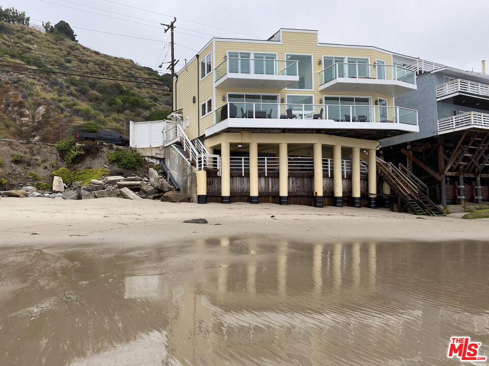The moment you step into the "Big Dog Beach House" you'll be awed by the expansive ocean views and open living and dining spaces with a beautiful kitchen oriented for the stunning beach views. The downstairs living room has a built-in entertainment cabinet and wet bar, plus a one-of-a-kind handmade seashell gas fireplace surround. Wooden ceilings, recessed lighting and hardwood floors give the space warmth and charm. The entry, dining room, and kitchen floors are covered in tile chosen for it's old world beach aesthetic and practicality. Throw open the Fleetwood sliding glass doors and take in the soothing sea breezes! The kitchen has charming European backsplash tiles, Viking range and French door double oven with two dish drawers, built-in microwave, and Sub-Zero refrigerator. Upstairs, the primary bedroom boasts a private deck, elevated fireplace and wood details. You'll enter the primary bath past two walk-in closets and a sauna as well as a privacy shower and soaking tub. Double sinks and natural lighting beckon. The secondary bedroom can easily be used as an office and/or den and has its own deck as well. The versatile third bedroom can also serve as a den, work-out room or guest bedroom. Each bedroom has it's own spacious bathroom. Exit the back door and grab a towel and a beverage to go downstairs to the expansive entertainment deck. Lighting and state-of-the-art heaters make this area fun year-round. There's plenty of storage behind the wooden doors and an outdoor privacy shower once you've come up from the beach! Located a few minutes away from the Malibu Pier and Santa Monica!
