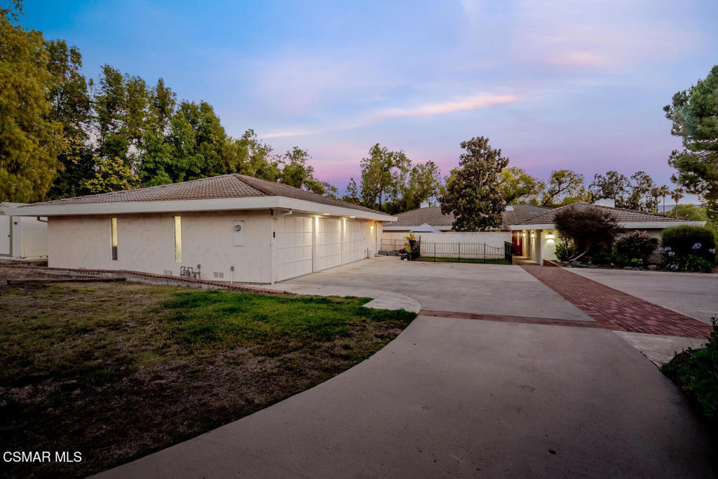 Single-Story Mid-Century Modern Lake View Home with detached ADU/Guest House on One Acre - Horse Zoned! Welcome to this rare, single-story home with 2,544 sqft of living space, situated on almost a completely flat acre on Sinaloa Lake, offering full lake membership, lake views, and direct trail access. Horse-zoned and ideal for those seeking space, the property includes ample parking for RVs, boats, off-road vehicles and guests. The main home features three bedrooms and two and a half bathrooms, with natural light flowing through large windows. Saltillo tile floors extend through the family room with built-ins and adobe style fireplace with limestone hearth. The spacious, west-facing kitchen overlooks Sinaloa Lake. The kitchen is outfitted with cherry wood cabinets, granite countertops, a center island, Sub-Zero refrigerator, stainless steel appliances, and a skylight with auto-opener. A separate living room includes a fireplace with limestone hearth and French doors leading to a private courtyard. The primary suite offers built-in cabinetry, a marble fireplace, custom lighting, and access to a private courtyard. The fully renovated primary bath features a Japanese soaking tub, dual vanities, and a large custom-tiled walk-in shower. Two additional guest rooms are located on the opposite wing, along with a full guest bathroom with a dual vanity and pocket door to the toilet area. The detached 750 sq ft ADU includes its own HVAC and features a full kitchen with cherry cabinets and granite countertops, a spacious family and dining area, bedroom, bathroom with shower, and laundry. High ceilings and luxury vinyl flooring complete the unit, which also has its own private garden. Outside, enjoy multiple outdoor seating areas to take in the sunsets, raised patio with lake views, and access to private trails. Mature fruit trees- orange and pear- are located throughout the property. An oversized three-car garage includes space for your classic car collection, a large workshop, half bath and extra storage. This is a one-of-a-kind opportunity in Simi Valley--private, spacious, and designed for both daily living and entertaining.