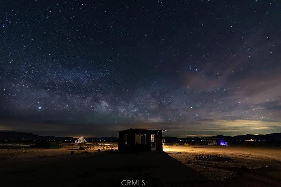 This is a unique remodeled cabin with an enclosed garage secondary living space. Many possible uses for this property. Perfect for artist retreat or desert getaway home. The five-acre parcel has six concrete slab spaces with dedicated parking. There is a toilet and three showers on septic system installed in 2022. The property is off grid with six 200 watt solar panels and batteries. It is hauled water with two separate 300-gallon storage tanks. The main cabin has recent metal roof that has been torched down for resistance to wind. Easy access from Amboy Road. Located just minutes away the Palms Restaurant. The stars at night and expansive vistas have to be experienced in person.