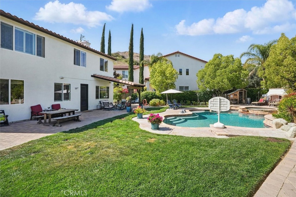Say yes to a life of comfort, elegance, and opportunity at 29160 Harmony Way—a home with heart, history, and the promise of new beginnings. Tucked away in the prestigious gated community of Bella Vida in beautiful Saugus, this tranquil sanctuary is more than just a residence; it’s a place waiting to be filled with laughter, gatherings, and memories that last a lifetime.
This thoughtfully maintained home is now searching for its next chapter—an owner who will appreciate its four spacious bedrooms, four full bathrooms, and flexible layout designed for comfort and adaptability. It also includes a large gym that can double as a fifth bedroom, and a versatile den with its own closet—ideal as a nursery, home office, or guest suite—perfect for a variety of living arrangements.
Inside, you’ll find a seamless blend of elegance and functionality. The open-concept layout features a chef’s kitchen with a spacious walk-in pantry, dual sinks, granite countertops, and built-in reverse osmosis and whole-home filtration systems for sustainable, everyday ease. The home’s eco-conscious features include energy-efficient solar panels, dual-zone air conditioning, and a recently upgraded water heater. The laundry room, located on the first floor, includes a built-in sink, ample storage, and an adjacent mudroom for extra organization.
But it’s the outdoor space that truly elevates this property. Set on one of the largest lots in Bella Vida, the backyard is an entertainer’s dream and a private escape. A sparkling pool and spa offer resort-style relaxation, complemented by a cozy outdoor fireplace. The space includes raised garden beds, a chicken coop, a gated side area perfect for pets, and a secondary side yard with a dog run leading to a convenient storage shed—all within a beautifully landscaped and secure setting.
The Bella Vida community itself is known for its safety, serenity, and friendly atmosphere. Living here means enjoying peace of mind behind the gates, surrounded by like-minded neighbors and easy access to parks, trails, and top-rated schools in the Saugus Union School District. Just minutes from Central Park, major commuter routes, and the Santa Clarita Metrolink station, this location effortlessly blends convenience with quality of life.
Harmony way is where morning coffees become traditions, summer nights stretch under starry skies, and every corner holds the potential for something meaningful. Come see how life feels in Harmony.