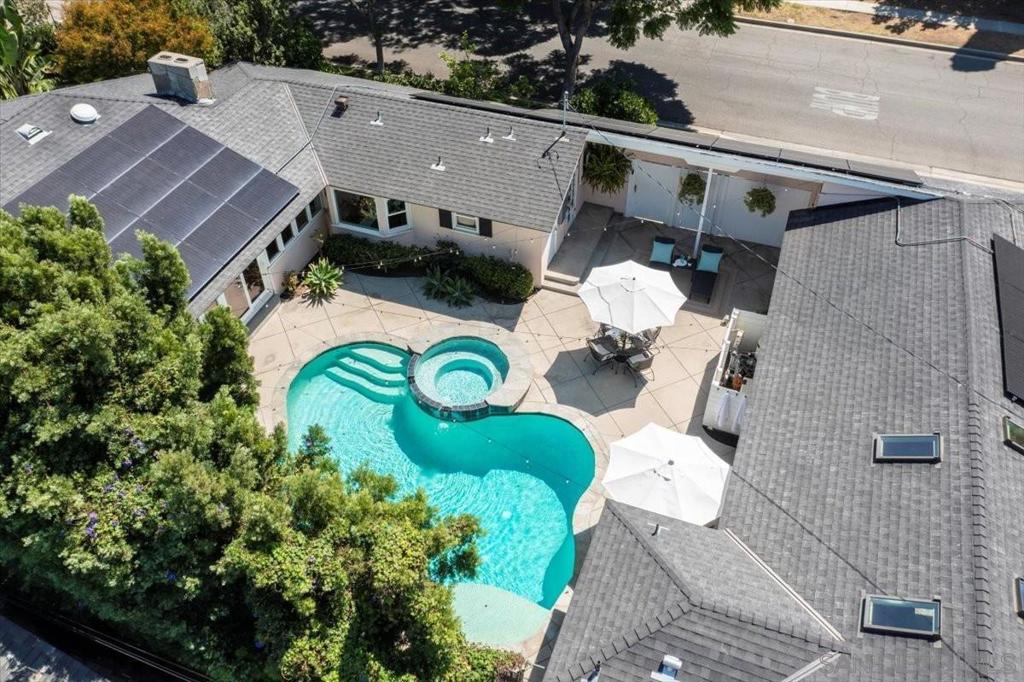 Welcome to this custom-built 1950s Ranch-style home centrally located in one of the most historic and desirable neighborhoods in Orange County. With only two owners since construction, this property offers a rare opportunity to own a timeless residence enhanced with modern upgrades. Spanning 2,900 sqft, the home features 4 bedrooms, 3.5 bathrooms, and an open layout designed for seamless indoor-outdoor living. Hardwood floors lead to light-filled living and dining areas, all overlooking the sparkling pool and backyard retreat. The upgraded kitchen includes stainless steel appliances, black granite countertops, Carrera tile, a breakfast nook, and butler’s pantry with built-ins opening to the breezeway and pool—perfect for entertaining. The primary suite opens directly to the pool and features an ensuite with Italian marble floors and a Steam Mist shower. Additional baths showcase both modern and vintage touches, including a cast-iron clawfoot soaking tub. A detached poolside studio with kitchenette and ensuite offers flexible use as a guest house, ADU, or second primary suite. Outdoors, lush landscaping surrounds the home with mature roses, hydrangeas, citrus trees, Japanese maple, and camellias. Flagstone details flow from the front entry to the fireplace and pool deck, tying the design together. Modern amenities include solar panels, dual Tesla Powerwalls ready for EV hookup, and an energy efficient instant hot water heater. This CA Resort property is less than 10 min from Disneyland, centrally located near freeways, shopping, schools, parks, museums and dining.