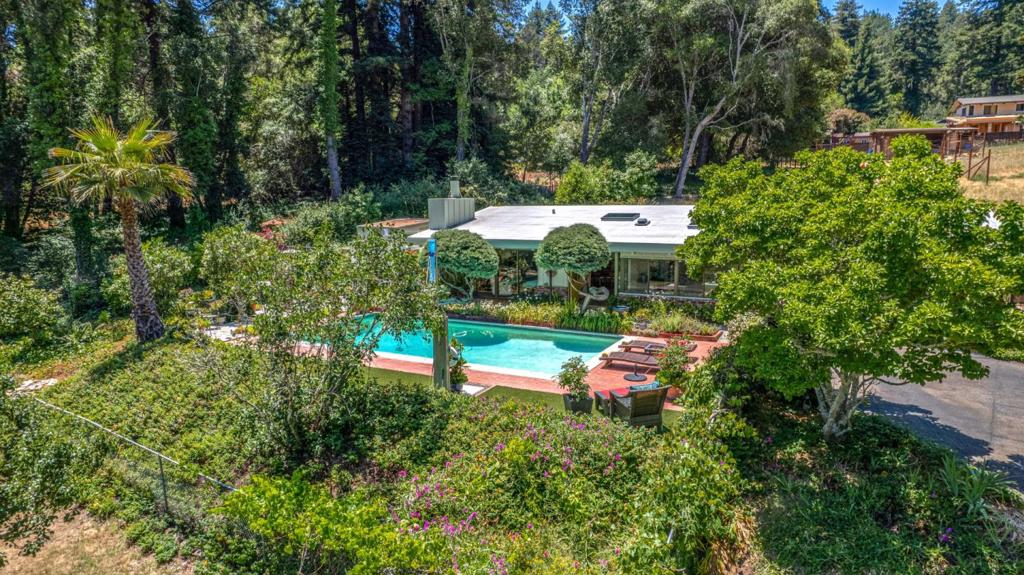 Impeccable home, grounds, and location. Wake to the quiet charm of close to town country life, where deer and wild turkey wander through gently sloping terrain. Start each day with coffee at the kitchen table, taking in views of lush gardens and a sparkling pool, all bathed in golden morning sunlight. With an orchard just beyond, this idyllic property is a nature lovers haven, an inviting retreat for those seeking space, serenity, and rural elegance. Just 1/4 mile from downtown Felton, this sunny, single-level home offers 1,602 square feet of living space, an attached garage, workshop, and laundry. Inside, you'll find LVP floors, abundant skylights, and an open, airy feel throughout. The 3-bedroom layout features a second bedroom with its own private shower, making it ideal for guests or extended family. Each room has charm and comfort, with beautiful natural light and peaceful views. Enjoy the quiet of country living with the ease of being moments from local shops, cafes, and scenic trails at nearby State Parks like Henry Cowell, Fall Creek, and Roaring Camp. A rare blend of location, light, and livability awaits. Two parcels combine for nearly an acre, with separate driveways on the main and upper lots, perfect for RV parking or boat storage. Santa Cruz beaches are 20 min away.