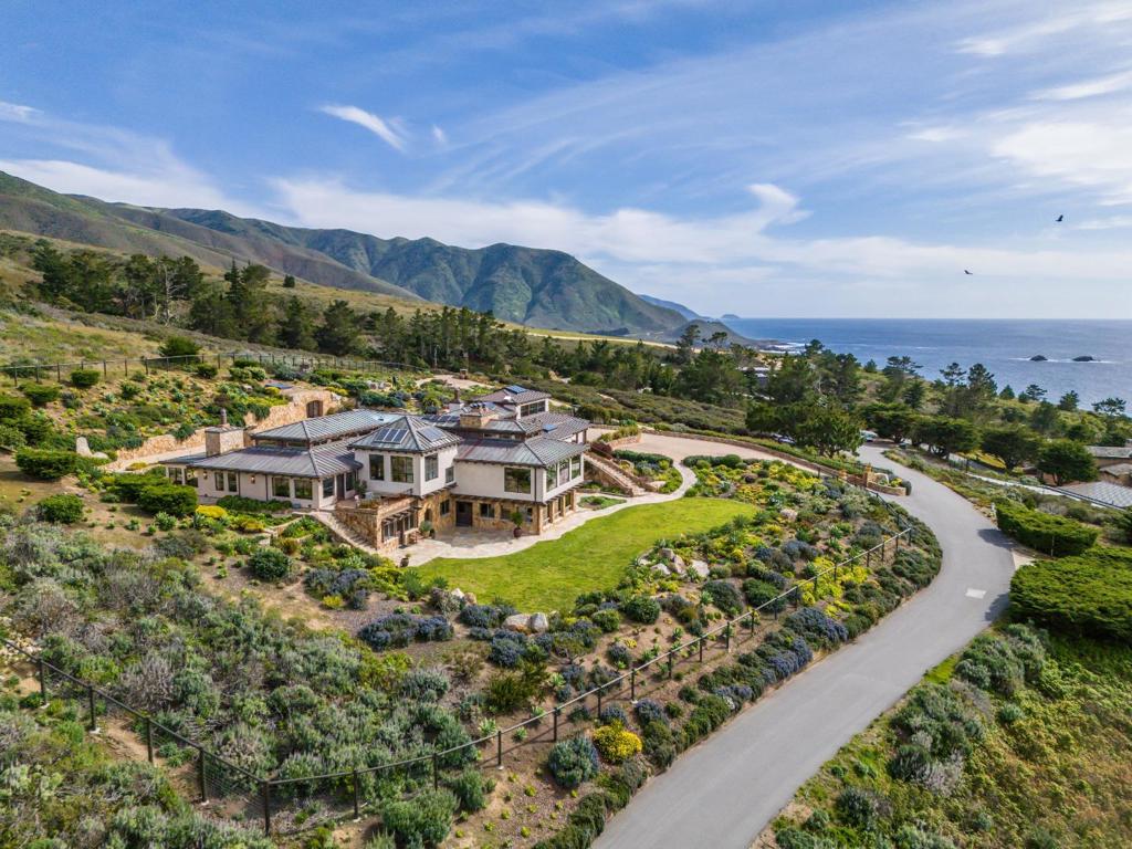 Set between the dramatic Carmel coastline and the Santa Lucia Mountains lies a private retreat in perfect balance with land and sea. Stone steps lead to this five-bedroom, six-bathroom contemporary coastal chalet, where a tiled foyer and vaulted, beamed ceilings create an immediate sense of grandeur. At its heart, a living room with a stone fireplace and soaring ceilings is bathed in light from expansive windows and skylights, offering stunning views from Yankee Point to Big Sur. The chef's kitchen features custom cabinetry, a spacious island, and a breakfast bar, flowing seamlessly into the dining room, bar, and outdoor BBQ space. The primary suite is a luxurious retreat with ocean views, a wood-burning fireplace, terrace access, and a spa-like bath with a walk-in closet. Four additional bedrooms offer comfort for family and guests. Outside, enjoy a pool, hot tub, pizza oven, grill, and firepit terrace surrounded by beautifully landscaped grounds. Additional highlights include a home theater, sauna, wine cellar, dual offices, and a private guest suite with its own entrance and full amenities. This rare estate in Victorine Ranch offers timeless beauty, privacy, and a legacy of luxury just minutes from downtown Carmel.