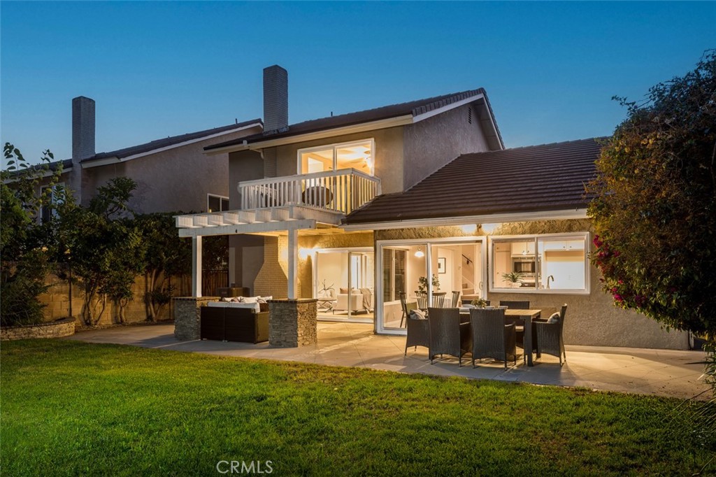 Set within the sought-after Forest Creek neighborhood of Lake Forest, this residence is designed with an emphasis on light, flow, and outdoor connection. From the street, the home presents a timeless façade softened by mature trees and a welcoming front entry. Inside, soaring ceilings and carefully considered sightlines create a sense of openness, while intimate zones balance the space for everyday living. The dining area sits beneath a wrought-iron balustrade, bridging the split-level floor plan and offering views across both living and entertaining spaces. Outdoors, the rear garden has been curated as an extension of the interior living spaces. A covered patio with stone-wrapped posts offers an ideal setting for open-air dining and evening gatherings, while the expansive lawn delivers room to play, relax, or further personalize. Upstairs, the primary suite opens to a private balcony overlooking leafy treetops, a retreat framed by sliding glass doors that invite in natural light and breezes. The secondary bedrooms provide equal comfort, each designed with flexibility in mind for family, guests, or work-from-home needs. Complementing the home’s private comforts are the exceptional amenities of the surrounding community. A short stroll leads to the residents-only Sun and Sail Club, where resort-like offerings include multiple pools, a spa, tennis and pickleball courts, indoor gym, and an array of sporting facilities. Moments from Lake Forest’s schools and trail networks, this home combines neighborhood tranquility with modern suburban ease, a thoughtful setting for both quiet retreat and lively entertaining.