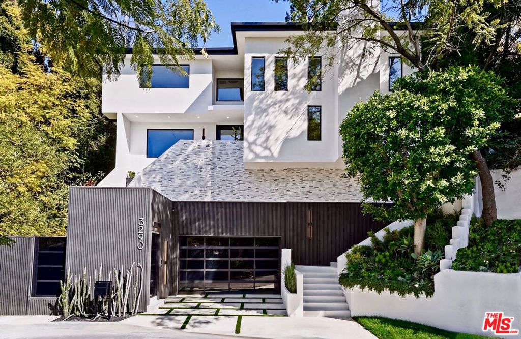 Stunning, newly rebuilt architectural masterpiece in the exclusive Hollywood Knolls. Located on a quiet cul-de-sac street, this smart home is fully automated with cutting-edge Control 4 system. A dramatic 20-ft foyer opens to an expansive living space framed by Fleetwood windows and doors, showcasing sweeping views, flooding the home with natural light, and seamlessly blending indoor and outdoor living. The chef's kitchen features Italian cabinetry, sleek Miele appliances, designer fixtures, and a large waterfall island, perfect for entertaining and everyday living. Custom made Hubbardton Forge lighting throughout adds elegance and warmth. The huge primary suite is a private retreat with its expansive size and exquisite design. Two additional extra-large bedrooms provide ample space for an office, family, or guests. The home boasts multiple fireplaces, a spacious balcony, and a large deck that overlooks a beautifully landscaped grassy yard ideal for entertaining & relaxing. Private and secure with underground utilities (no unsightly poles or wires). Custom-built and meticulously designed with every detail thoughtfully curated. Located just moments from the major studios, Warner Bros, NBC, Universal, CBS, and Netflix. Walking distance to Lake Hollywood, walking & hiking trails, offering a perfect balance of city convenience and tranquility. This bespoke, move-in-ready home offers the ultimate in L.A. luxury and lifestyle.