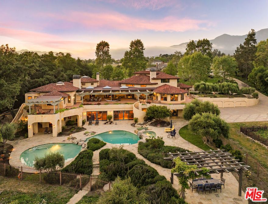 Magnificent Ojai estate nestled on approximately 3.8 acres, offering sweeping views of the Topa Topas, masterfully merges timeless old-world aesthetics with contemporary California artistry. This exquisite Mediterranean-style residencedesigned by acclaimed architect Marc Whitmanis a rare offering that combines privacy, elegance, and craftsmanship at the highest level. Curved lines, arched doorways, and cathedral ceilings set a tone of quiet grandeur. Inside, every detail has been meticulously curatedfrom solid walnut flooring and bespoke cabinetry to imported Spanish tiles, hand-forged chandeliers, and custom windows and hardware. The expansive living room, featuring multiple seating areas, a fireplace, and French doors, opens to a private library and a sunlit patio, perfect for indoor-outdoor living. The gourmet kitchen, with top-tier appliances and panoramic views, is both a culinary haven and a gathering place. The primary suite is a sanctuary with two sitting areas, a fireplace, double doors to a private terrace, stunning mountain vistas, generous closets, and a spa-inspired bathroom. Three guest bedrooms, each with ensuite bathrooms and access to patios and gardens, offer ultimate comfort and privacy. A fifth bedroom occupies the top levelcomplete with a loft, fireplace, and two balconiesideally suited for an office, studio, guest retreat, or live-in support. With multiple bedroom suites and separate living zones, the estate offers exceptional flexibility for multi-generational living or those seeking refined personal space. The top-level suite also serves as a unique option for a private executive office or creative retreat. Seamless transitions from the interior to the outdoorsthrough French doors and strategically placed terracesextend the living experience to sunlit decks, lush gardens, and an inviting pool area. Whether envisioned as a full-time residence, a luxurious second home, or a legacy investment, this estate is a rare opportunity to own an architectural masterpiece in one of Ojai's most exclusive enclaves.