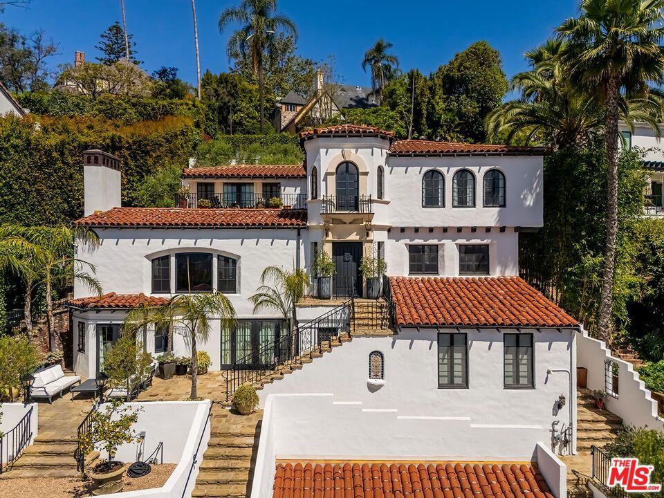 Meticulously curated Spanish stunner perched in the coveted hills of Los Feliz. This fully furnished entertainer's home features multiple indoor and outdoor living and dining spaces to optimize the California lifestyle. Panoramic views of the Los Angeles skyline visible from almost every room and multiple patios provide a jaw-dropping backdrop to everyday living. Upon entry, the formal living room anchored by a massive stone fireplace boasts original beams, a baby grand piano and designer furniture. Across the foyer sits the formal dining room complete with seating for 8 and windows flooding the room with light. A large chef's eat-in kitchen with ample storage and counter space opens to the picturesque back patio with outdoor dining and living. The main level bedroom, currently furnished as an office, offers a convenient and private workspace nearby to a full bathroom with designer tile. Up the colorfully tiled stairs sits the primary suite with a large en-suite bathroom with a walk-in shower and large soaking tub adorned with windows. Two additional guest bedrooms, one featuring a stunning front facing patio, and two full baths complete the second story. The lower level boasts a large family room with a bar, rich coffered ceiling and french doors to the sunny patio with views. Double doors open to an exquisitely designed office with plenty of built-in storage and regal fireplace. A spacious gym with views, a beautiful spa-like bathroom and attached two car garage complete this amazing property.