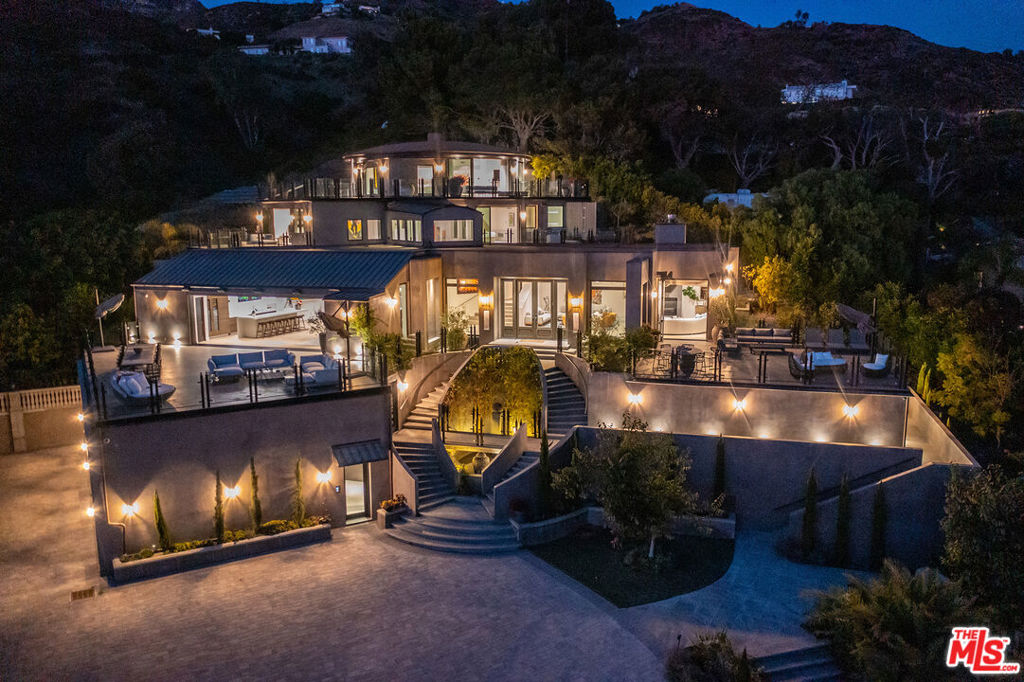 Discover the ultimate in elegance and tranquility in this ultra-private gated Malibu compound situated on over 7 acres with private access to Lechuza beach and endless sunrise-to-sunset ocean views. Enter through the private front gate to the long driveway that winds up past the 1 bedroom/1 bath guard house, pool pavilion, and tennis court and leads to the incredible newly-built main house. This Contemporary estate offers a chic style and serene setting with the ultimate indoor/outdoor flow. Walls of glass throughout lead to massive decks overlooking breathtaking panoramic views from Point Dume and Zuma Beach to the Channel Islands. The main level features open concept living seamlessly fusing interior and exterior spaces and offering incredible space for entertaining. The grand gourmet kitchen features Italian marble counters and wood cabinets, professional appliances, and a large built-in bar. Ascend the staircase or take one of three elevators to the upper level primary suite that was designed in a circular layout with wrap-around deck and walls of glass capturing the intoxicating panoramic ocean views. The main house also features three additional en-suite bedrooms, each with their own private decks, and a full-sized state-of-the-art theater. The grounds of this incredible compound leave nothing to be desired, featuring a North/South private tennis court, palm garden, heated pool and spa with dual waterfalls, and over-water bridge leading to the circular pool house complete with interior and exterior living rooms, built-in bar, and full guest suite. This smart home is completely automated and can be controlled from touch screens or via the HomeLink Connect App, making it easy to manage from anywhere. This exceptional Malibu compound offers the ultimate resort lifestyle in one of the more desirable beach cities in the world.