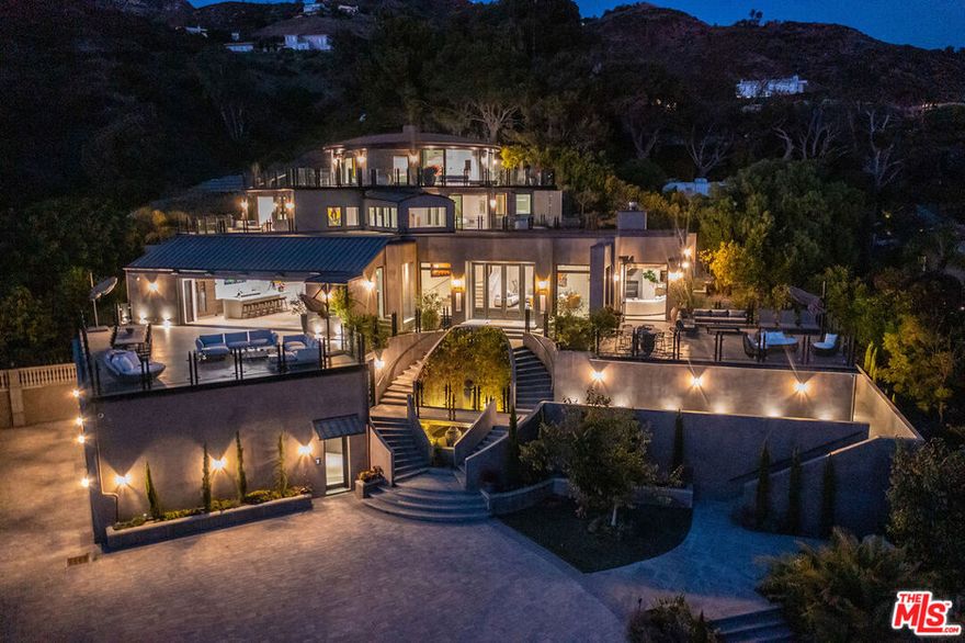 Discover the ultimate in elegance and tranquility in this ultra-private gated Malibu compound situated on over 7 acres with private access to Lechuza beach and endless sunrise-to-sunset ocean views. Enter through the private front gate to the long driveway that winds up past the 1 bedroom/1 bath guard house, pool pavilion, and tennis court and leads to the incredible newly-built main house. This Contemporary estate offers a chic style and serene setting with the ultimate indoor/outdoor flow.  Walls of glass throughout lead to massive decks overlooking breathtaking panoramic views from Point Dume and Zuma Beach to the Channel Islands. The main level features open concept living seamlessly fusing interior and exterior spaces and offering incredible space for entertaining. The grand gourmet kitchen features Italian marble counters and wood cabinets, professional appliances, and a large built-in bar. Ascend the staircase or take one of three elevators to the upper level primary suite that was designed in a circular layout with wrap-around deck and walls of glass capturing the intoxicating panoramic ocean views. The main house also features three additional en-suite bedrooms, each with their own private decks, and a full-sized state-of-the-art theater. The grounds of this incredible compound leave nothing to be desired, featuring a North/South private tennis court, palm garden, heated pool and spa with dual waterfalls, and over-water bridge leading to the circular pool house complete with interior and exterior living rooms, built-in bar, and full guest suite. This smart home is completely automated and can be controlled from touch screens or via the HomeLink Connect App, making it easy to manage from anywhere. This exceptional Malibu compound offers the ultimate resort lifestyle in one of the more desirable beach cities in the world.