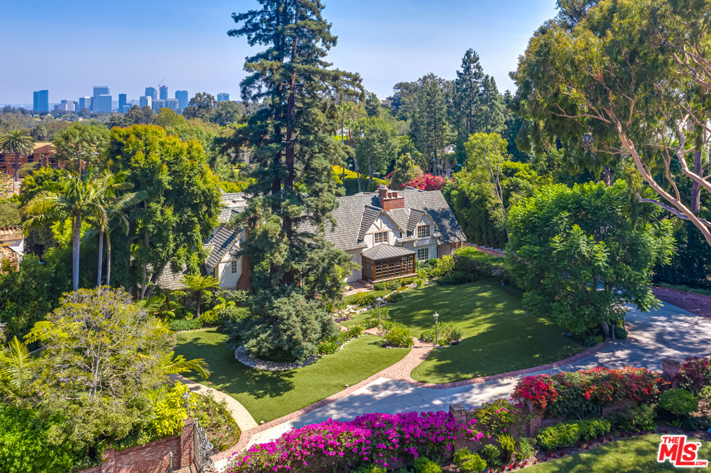 This grand English manor house sited on almost one acre in prime Old Bel Air was once the estate of famed filmmaker Otto Preminger when Hollywood greats occupied many of these lavish homes. This extraordinary property evolved through the years to accommodate entertaining on a grand scale. The formal living room and lounge opens to a dramatic rotunda with soaring domed trompe-l'oeil ceiling. A breathtaking chandelier is the center of attention! A banquet sized dining room has views of the brick terrace with topiaries, flower beds and oval pool. Walls of the richly paneled library conceal an elevator that opens to all 3 stories. A luxurious master suite with sitting area and fireplace opens to the master bath with garden views. Spiral stairs bring you to room after room of custom closets, also reached by the elevator. Purists will love this irreplaceable home. To enhance it, there is much with which to work!