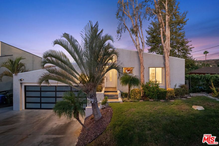21694 Yucatan Avenue is 4-bed 3-bath home with jaw-dropping views on a street to street lot in the coveted Girard Tract south of the Boulevard. Step inside and you're immediately met with soaring ceilings, drawing your eye through the living room to sweeping skyline views. An open layout connects the living room, double-sided fireplace, kitchen, dining, and second living area - all designed to showcase light and views. The spacious primary suite opens to a private veranda, where you can wake to sunrises that feel like your own private show. The ensuite bathroom features double sinks, a jetted tub, separate shower, private water closet, walk-in closet, and ample storage. The lower level includes three bedrooms and a full bath with double sinks. A spacious guest room or home office on the entry level is complemented by an adjacent guest bathroom with a shower offering flexibility for guests or work-from-home comfort. A two-car garage with direct access and dedicated laundry area add everyday convenience. Enjoy peace and privacy with easy access to Ventura Boulevard's dining and shopping, Topanga Westfield Mall, and the area's beautiful parks and hiking trails.