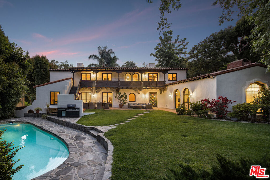 Welcome to a once-in-a-generation opportunity to own one of Hollywood's most iconic and storied estates. Nestled in the coveted Outpost Estates, this 1929 Spanish Colonial Revival masterpiece was the beloved longtime residence of legendary television host Bob Barker. Painstakingly restored and masterfully reimagined by acclaimed interior designer Julia Dempster, this extraordinary property embodies the romance of Old Hollywood with the sophistication of contemporary luxury. Built atop the site of "The Outpost" the original adobe home that marked the birth of Hollywood itself this landmark residence holds the rare distinction of being Los Angeles Historic-Cultural Monument No. 673. With a provenance as rich as its design, 1851 Outpost Drive is far more than a home; it is a chapter of Los Angeles history. The estate features six spacious bedrooms, six luxurious bathrooms, and a formal powder room on the main level. A 601-square-foot basement includes a sauna and two additional rooms ideal for guests, an office, or a gym. A stylish home office with an en-suite bath doubles as a guest suite or studio. Throughout the home, original architectural details have been carefully preserved from the hand-painted fresco ceiling and grand arched doorways to the original stained-glass windows and the iconic bar tucked inside the wood-paneled library. The dramatic living room fireplace and sweeping scale of the interiors speak to a time of Hollywood grandeur. Dempster's year-long restoration imbues the home with natural textures and warmth, using Roman clay and limewash finishes to soften the walls and amplify the light. The chef's kitchen is a masterclass in form and function, featuring custom white oak cabinetry, Thermador appliances, and breathtaking Viola Monet marble across the island, countertops, and backsplash.The home benefits from two stunning primary suites. The main primary suite features a dream walk-in closet and luxurious his-and-hers bathrooms, offering the ultimate in privacy and indulgence. The second primary suite also boasts dual closets, providing generous storage and flexibility for guests or extended family. The primary suite's bathroom is a sanctuary unto itself, with a show-stopping book-matched travertine shower and marble thresholds that echo throughout the residence. European white oak floors run seamlessly underfoot, while hand-selected Zia tiles add character and craftsmanship to the secondary baths. An integrated infrared sauna offers a quiet moment of wellness and restoration. Outside, the grounds evoke a private resort: a generous pool, an expansive lawn, and a towering oak tree create a serene retreat just moments from Runyon Canyon, the Sunset Strip, and the cultural pulse of Hollywood. With its unparalleled location, cinematic history, and world-class design, 1851 Outpost Drive is not simply a residence it is a legacy awaiting its next custodian.