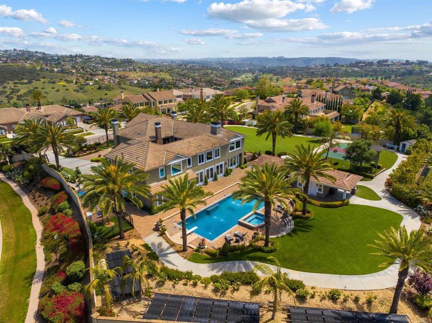 Tucked behind private gates in the exclusive Magnolia Estates enclave of Bressi Ranch, this elegant custom home spans approx. 6,219 sq.ft. on a rare 1.56-acre corner lot, the largest in the neighborhood. With 5 bedrooms, 5.5 baths, and versatile spaces including a media room, private office, library, and craft room, this home was designed for both luxury and function. A dramatic foyer with a sweeping staircase and soaring coffered ceilings sets the tone for this grand residence. The resort-style backyard features a heated saltwater pool with 10-ft deep end, fountains, spa, and a pool house complete with bath, laundry, outdoor shower, and a fun wine lounge. An expansive outdoor kitchen with BBQ, fireplace, and seating makes entertaining seamless. The grounds also include a batting cage (with Petco Park dirt!), half basketball court, treehouse with WiFi, and a canine courtyard. For garden lovers, there’s a fruit orchard, raised flower beds, chicken coop, and garden shed. The chef’s kitchen features dual islands, a pot filler, built-ins, walk-in and butler’s pantries, and a sunny breakfast nook. The primary suite offers a fireplace, spa-like bath, and custom walk-in closets. A main-level en-suite guest room is perfect for visitors, while upstairs, two secondary bedrooms feature a Jack and Jill bathroom, each with their own sinks and custom built-ins. Bonus rooms include a library, bright craft space, and spacious media room. Additional perks include fully owned solar, backup generator, 30+ security cameras, 4-car garage, newer HVAC, updated water heater, whole house water purifier, intercom system, emergency water storage, and smart control QuietCool attic fan. Located near top schools, golf, dining, and our stunning coastline, this is Bressi Ranch living at its finest. Whether you’re relaxing poolside or entertaining under the stars, this home delivers privacy, luxury, and lifestyle. See attached documents for additional information, floorplans or visit the website - this home truly has it all! Buyer and buyer’s agent to verify all info in MLS prior to COE.