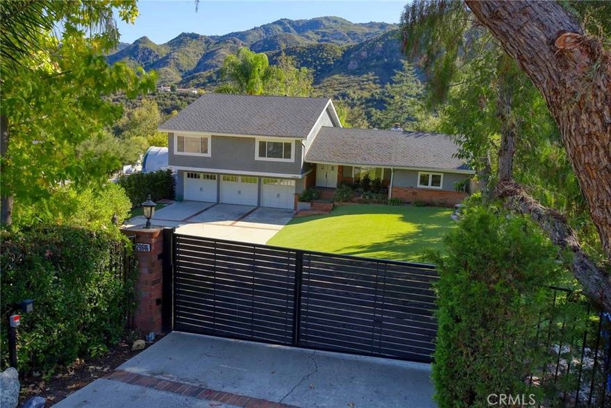 Tucked away down a long, gated private driveway and nestled within a secluded enclave surrounded by the majestic Santa Monica Mountains—just minutes from Malibu—lies this hidden gem sure to impress even the most discerning buyer. This split-level home offers a seamless open floor plan designed for both intimate gatherings and lively entertaining. Fully updated throughout, it features rich wood flooring, soaring vaulted ceilings, and multiple skylights that bathe the living spaces in natural light. A stunning double-sided fireplace anchors the great room, creating a warm and inviting ambiance on cool mountain evenings. The chef’s kitchen is a true centerpiece, boasting quartz countertops, stainless steel appliances, a walk-in pantry, and a professional-grade WOLF range—perfect for culinary enthusiasts. Upstairs, you’ll find three spacious en-suite bedrooms and a dedicated office. The primary suite impresses with vaulted ceilings, a generous walk-in closet, dual vanities, a deep soaking tub, and breathtaking mountain views. The lower level—with its own entrance—offers incredible flexibility, complete with a family room, bedroom, and full bath. Whether used as a guest suite, creative studio, multi-generational living space, or home office, the possibilities are endless. Outdoors, the tiered backyard is a private oasis and an entertainer’s dream. Swim laps in the sparkling pool, relax beneath one of the charming gazebos, or unwind on the expansive deck surrounded by nature’s beauty. As evening falls, the tranquil atmosphere is often accompanied by the melodic calls of wild peacocks echoing through the canyon—reminding you just how special this setting truly is.