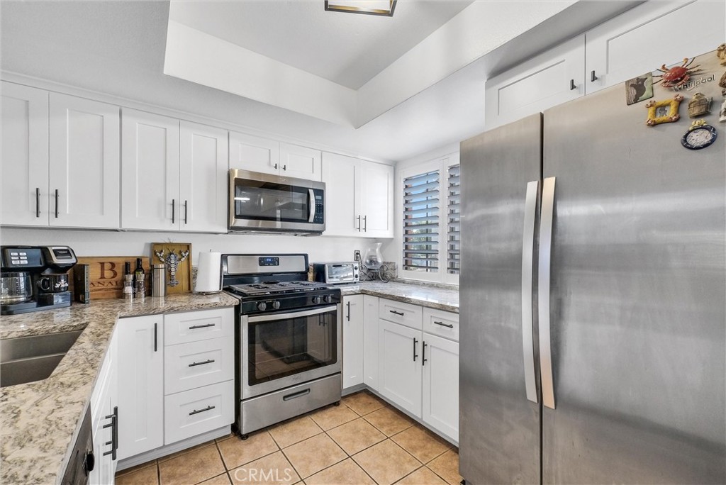 Welcome to this beautifully updated and thoughtfully designed townhome in the charming Stratford Village community of Ontario, ideally located just steps from the pool and clubhouse. Brimming with warmth and natural light, this inviting home showcases soaring vaulted ceilings, fresh neutral-tone paint, and wood-style flooring that flows through the open-concept living and dining area, complete with a cozy fireplace perfect for cool evenings. The bright, modern kitchen features crisp white cabinetry, gleaming granite countertops, stainless steel appliances including a refrigerator, dishwasher, and stove, plus stylish hardware and lighting accents. Upstairs, you'll find a generously sized bedroom with a walk-in closet and an updated full bath with quartz countertops and contemporary finishes. A washer and dryer are conveniently included, making everyday living easy. Step outside to your own private patio oasis, ideal for morning coffee, peaceful evenings, or weekend barbecues with friends. Adding even more value, this home offers a one-car garage, an assigned covered parking space, and access to community amenities—all wrapped in a friendly, well-maintained neighborhood setting. Close to shopping, schools and freeway access.