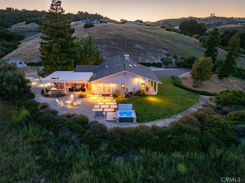 A rare opportunity to own 6+ acres in one of the best locations in all of Paso Robles, with breathtaking views and a gorgeous fully remodeled three-bedroom home. Buy it fully furnished as your forever home, a vacation home, and/or continue on as one of the most successful vacation rentals in Paso. Experience Paso Robles in style at this spectacular property, fondly known as Illumination Ridge! Open the door to this stylish home and behold a chandelier of luminous handblown glass orbs illuminating over an open and airy entertainer's paradise home. A home renovated with sleek zinc counter tops and hip designer stones, balanced with touches of hand-stained wine bottle pallets and other unique reclaimed rustic wood. Gather with your family or friends in the beautiful open living area with fireplace. Hang out on sleek bar chairs next to the cool zinc counters in the open gourmet kitchen while you whip up a tasty morsel using the powerful 6-burner range, grab a glass from the most beautiful bar you will encounter in Paso. Oh and unwind! There are two oversized ensuites or a chic third bedroom, each with its own bathroom. Stroll outside through any of the french doors positioned throughout this home. Exhale and leave your angst behind as you take in the breathtaking views that include rolling hills with almond trees and peaks of vines on one side juxtaposed next to sweeping views of the city on another. As the sun begins to set, you will be challenged to decide where you should sit to enjoy the awesome views of the bright city lights intermingled with the emerald greens of the rolling hills. Perhaps you will choose to lounge around the chic outdoor sofa, slip into a chair at the 12 ft. long teak outdoor dining table, grab an adirondack chair around the fire-pit, or stretch out in adirondack loungers, or stroll over to numerous secluded sitting areas located throughout the grounds.
You can turn up the grill on the gas BBQ or fire up some fragrant wood in the commercial-sized Santa Maria grill and throw on your favorites from a local grower for a mouth-watering dinner in true Paso Robles style. Play petanque or bocci ball in the ball court, throw some horseshoes, stroll the grounds, lounge in the Jacuzzi, then relax sitting around the fire pit while you contemplate life. This is the perfect blend of city and country life and all its' waiting for is you. Welcome to Illumination Ridge - a perfect marriage of outdoor and indoor living at its stylish best!