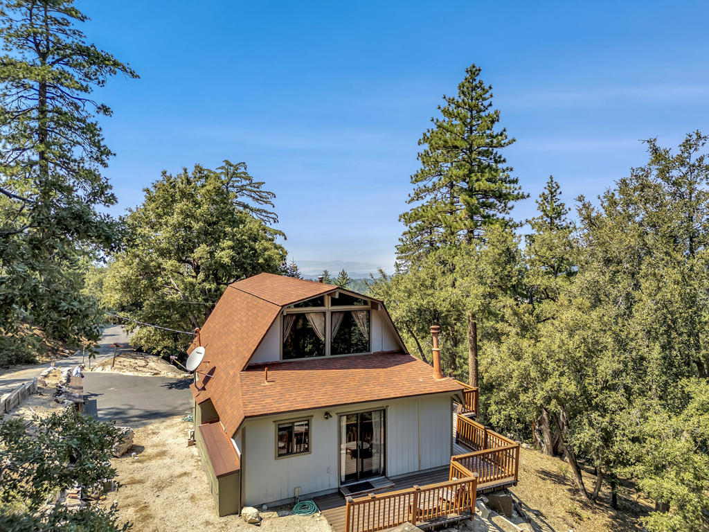Welcome to your peaceful getaway at 53050 Woodpecker Way in Idyllwild's coveted Stonewood neighborhood. This charming 2-bedroom, 2-bathroom home offers privacy on a spacious 37,026 square foot lot. Enjoy stunning mountain ridge and Diamond Lake views from the expansive composite deck, perfect for relaxation or entertaining. Step into the inviting open living area, featuring vaulted ceilings and a cozy wood stove. The renovated kitchen, with granite tile counters, breakfast bar, and modern cooktop, is perfect for culinary adventures. The primary bedroom includes a wood stove, ample closets, a luxurious bath with a two-person tub, and deck access. A second bedroom and full tiled bath complete the main floor. Upstairs, an oversized loft offers versatile space with access to an upper deck showcasing breathtaking views. Dual pane windows, laminate and tile floors, and full furnishings make this home move-in ready. Ideal as a weekend retreat or year-round residence, this home provides the perfect blend of comfort and tranquility in the heart of the forest.