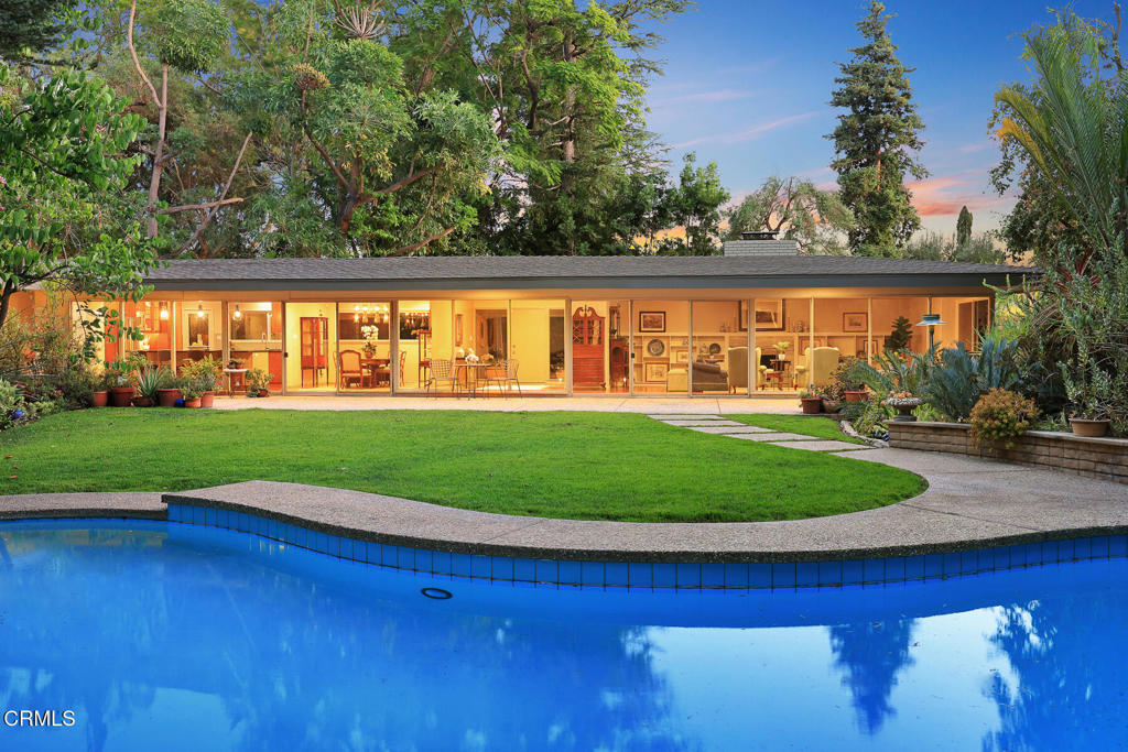 Idyllic Mid-Century Pasadena Estate with Seamless Indoor-Outdoor Living. Tucked away on 'Millionaires Row' a long, gated driveway, leads to a stunning 1953 single-story contemporary estate offering rare privacy and tranquility in the heart of Pasadena. A gracious porte-cochere entry sets the tone for the serene elegance that defines this exceptional residence. Step inside the formal entry, where custom built-in closets provide both style and function, and your eye is immediately drawn to the breathtaking 180-degree view of the lushly landscaped rear grounds. Walls of glass and sliding doors frame this picturesque setting, inviting natural light to flood the interiors and creating a seamless connection between indoor and outdoor living. The spacious living room features custom built-in bookshelves and a cozy fireplace--ideal for both quiet evenings and stylish entertaining. The formal dining area flows effortlessly into the beautifully remodeled kitchen, outfitted with high-end built-in appliances, a large center island, newer beverage refrigerator, and a discreetly tucked-away laundry closet. With 4 generous bedrooms and 3.5 bathrooms, the home is perfectly designed for comfortable living. The expansive primary suite is a true retreat, offering ample space and privacy. Rear grounds, professionally landscaped and dubbed the 'Circle Gardens' has been curated by noted local 3rd generation nursery family and rare plant collectors, the Burkard Family. The resort-like grounds are a private paradise--lush, exotic landscaping surrounds multiple seating areas, a sparkling pool, and three separate storage/garden sheds, offering endless opportunities for relaxation and recreation. A rare offering blending timeless architecture with modern convenience in one of Pasadena's most desirable and prestigious locations.