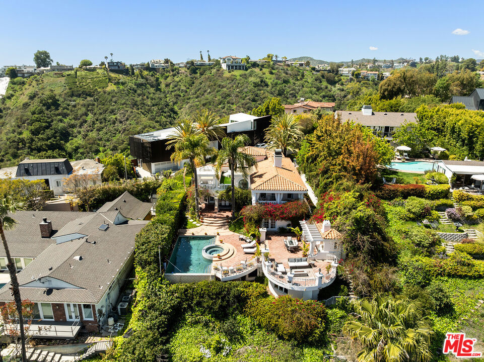 This spacious, gated two-story Contemporary Mediterranean estate is perfectly located on lower Stradella Road, offering breathtaking canyon, city, and ocean views. The property boasts rare off-street parking with a court for 6 cars, including a direct-entry 2-car garage. Inside, sunlit rooms feature wood floors, French doors, and beamed ceilings, creating an inviting and elegant atmosphere. The dramatic two-story stairwell, with its adjacent service bar, sets the stage for seamless entertaining. The entire second floor is dedicated to the owner's retreat, complete with a vaulted-ceiling sitting room, dual-sided fireplace, a generously sized bathroom, a large walk-in closet, and two scenic terraces offering stunning views. The resort-style yard is an entertainer's dream, featuring expansive patios, a BBQ center, an infinity-edge pool, a spa, a cabana bathroom, and unparalleled views. A large storage room is located beneath the rear patio. Set on a lush, private hillside lot of over 39,000 sq ft, this estate provides the ultimate in privacy and potential, making it a rare gem in the coveted Bel Air area.