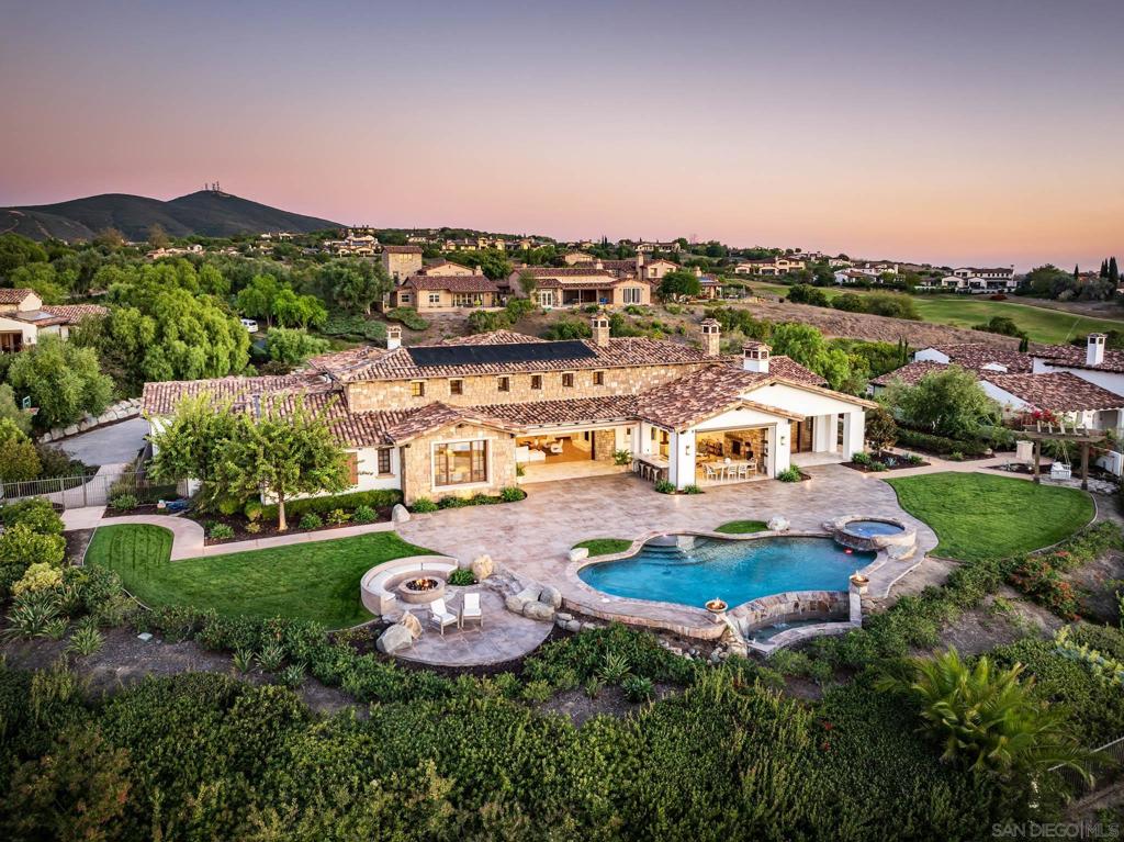 Perched above the 18th Green and Clubhouse in the prestigious guard-gated community of Santaluz, 8415 Run of the Knolls is a striking single-level estate that blends modern coastal luxury with serene natural beauty. Capturing sweeping panoramic ocean views, this architectural masterpiece spans approximately 6,872 sq. ft. and offers five en-suite bedrooms and 5.5 bathrooms, each designed for ultimate comfort and privacy. Set on over one acre of ultra-private grounds, the home features exquisite designer finishes, advanced smart-home technology, and seamless indoor-outdoor living spaces ideal for entertaining or relaxing in complete tranquility. As the sun sets, vibrant skies come alive with the glow of colorful hot air balloons drifting overhead — a signature Santaluz experience that enhances the property’s magical ambiance. With major Mello Roos bonds fully paid, this estate offers a rare opportunity to enjoy a resort-style lifestyle in one of Southern California’s most coveted golf course communities.  Framed by sweeping ocean horizons and nestled above the rolling fairways of Santaluz, 8415 Run of the Knolls is a rare opportunity to live an inspired coastal life — where architectural excellence, natural beauty, and everyday luxury converge.  This exceptional estate captures the very essence of modern California living, with expansive, light-filled interiors that flow effortlessly to panoramic outdoor spaces. Every vantage point invites connection to the landscape beyond — a seamless blend of refined elegance and serene tranquility.  Set on over one acre of ultra-private grounds above the 18th Green and Clubhouse, the single-level residence spans approximately 6,872 square feet and features five en-suite bedrooms and 5.5 bathrooms, each thoughtfully designed to deliver both comfort and privacy. Meticulously curated designer finishes, advanced smart home technology, and purposeful architectural details elevate every moment, transforming daily living into an artful experience.  Whether gathering with loved ones under vibrant sunsets or savoring peaceful mornings with the ocean as your backdrop, life here is defined by ease, beauty, and possibility. In one of Southern California’s most sought-after guard-gated communities, 8415 Run of the Knolls is more than a home  it’s an invitation to live extraordinarily. Major Mello Roos bonds have been fully paid.