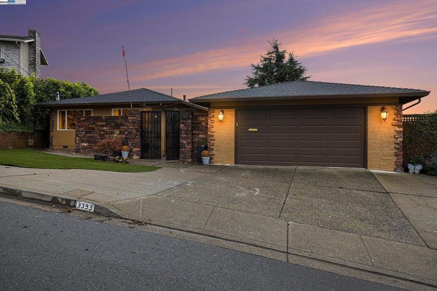 Welcome to this beautifully upgraded and expanded 3-bedroom, 3-bath Woodland Estates home, set on a generous 12,900 sq. ft. lot with approximately 2,200 sq. ft. of living space. This is a rare opportunity to own a property offering breathtaking panoramic views of the Bay, San Francisco, and the Bay Bridge. The open-concept floor plan is ideal for entertaining and features a gourmet kitchen with double refrigerator, high-end 48” stainless gas range, granite countertops, walk-in pantry, and stylish custom cabinetry. The spacious living area boasts vaulted open-beam ceilings and a decorative electric fireplace that adds warmth and character. The luxurious primary suite includes a walk-in closet and a beautifully appointed private bathroom. A second master bedroom provides added flexibility, while the third bedroom offers abundant natural light. A separate laundry room adds convenience. Energy-efficient upgrades include an owned 26-panel solar system. The detached, oversized 2-car garage features overhead storage and an electric car charger. Outdoors, you’ll find a synthetic front lawn and a low-maintenance backyard with pavers—perfect for gatherings while enjoying the afternoon sunset. Located in Woodland Estates, nestled among the oak trees and canyons of the Hayward Hills.