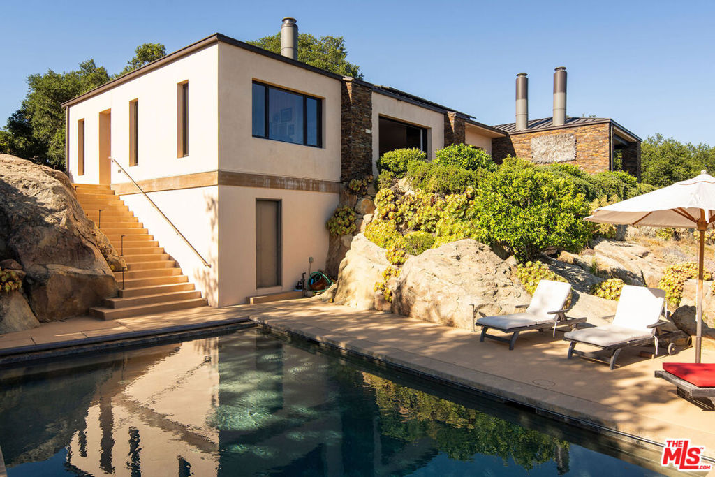 Set on 6.29 acres between Windemere Ranch and the Los Padres National Forest, this serene estate offers unmatched privacy and panoramic views converge in a setting that feels worlds away, yet is just 20 minutes from town. Completed in 2011, the thoughtfully conceived mini-compound is a masterclass in architectural harmony with the land. The 2 BD/2BA main house is designed to integrate seamlessly with the dramatic vertical rock outcroppings, with a second, standalone 2BD/1BA set in a tranquil pastoral setting offering additional comfort and flexibility. Enjoy private trails, an ocean-view pool, outdoor fireplace, and a producing orchard. A rare sanctuary immersed in nature's beauty. This is not just a property, it's a lifestyle of intentional living, immersed in the rhythms of nature.A Hidden Sanctuary of Privacy, Beauty, and Comfort Set in NatureDiscover the rare serenity of this captivating 6.29-acre (+/-) estate, where unmatched privacy and panoramic views converge in a setting that feels worlds away, yet is just 20 minutes from shopping, dining, and everyday conveniences.Nestled between the untouched expanse of the Los Padres National Forest and the renowned Windemere Ranch, this exceptional property is truly immersed in the embrace of nature. Completed in 2011, the thoughtfully conceived mini-compound is a masterclass in architectural harmony with the land. Designed to integrate seamlessly with the dramatic vertical rock outcroppings, the property offers a sense of sanctuary and wonder at every turn.The main two bedroom, two bathroom residence is positioned to capture sweeping vistas of the Santa Barbara coastline. Expansive, vanishing glass walls dissolve the boundaries between inside and out, inviting the Pacific, Channel Islands, and city lights into the home and creating a seamless indoor-outdoor lifestyle. Whether it's taking in the golden glow of sunset on the terrace by the outdoor fireplace, or enjoying coffee in the soft mist of morning, every moment here is framed in natural beauty.A second, standalone residence offering two bedrooms, one bathroom, and a kitchenette, features an equally stunning vantage point-complete with ocean views set in a tranquil pastoral setting. Ideal for hosting guests, extended family, or serving as a sophisticated work-from-home retreat, this secondary dwelling enhances the property's flexibility and appeal and is far enough from the main home for desired separation.The grounds are nothing short of enchanting. Wander through private trails shaded by native oaks, and soaring stone monoliths. Take a revitalizing swim in the ocean-view pool, or simply relax in the profound stillness that surrounds you. An orchard features numerous citrus, fruit, and avocado trees.This is not just a property, it's a lifestyle of intentional living, immersed in the rhythms of nature.Privacy. Luxury. Peace. Nature. This is your own piece of paradise, rarely available, and never to be replicated.