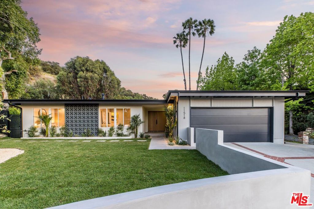 Nestled in the hills above Fryman Canyon, this 3BD/3BA Mid-Century home in Studio City is a timeless architectural gem. Originally designed by David Freedman AIA, the residence has been thoughtfully reimagined with elegant finishes, an airy open layout, and effortless indoor-outdoor flow. Upon entry, you're welcomed into an expansive living room featuring fluted accent walls, a sleek fireplace, and a striking atrium that infuses the space with natural light. The living area connects to the formal dining room, where sliding glass doors in both spaces open to the expansive backyard, perfect for entertaining. Built for a chef, the gourmet kitchen is appointed with high-end Thermador appliances, sparkling countertops, bar seating, and abundant cabinetry. The primary suite serves as a tranquil retreat, complete with a walk-in closet, additional built-ins, and direct access to the backyard. The en-suite bath features dual floating vanities and a luxurious walk-in shower with a custom, built-in bench. Two additional bedrooms, one with an en-suite bath are ideally situated near the primary, each filled with natural light and offering ample storage. Outside, enjoy a lush grass lawn, hillside vistas, and a built-in barbecue, ideal for dining al fresco. Located moments from Fryman Canyon's scenic trails and the highly acclaimed Carpenter Community Charter School, this home offers the perfect balance of comfort, elevated living, and utmost convenience.