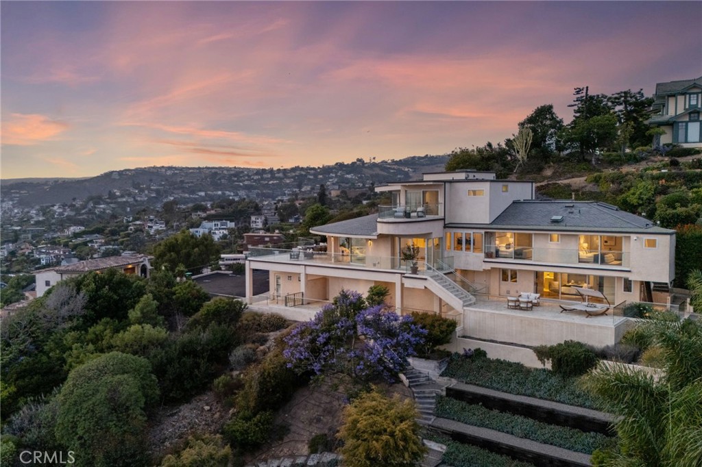 *** MODERN MASTERPIECE WITH UNRIVALED OCEAN VIEWS ***
Perched on a PRIVATE, STREET-TO-STREET LOT at the end of a QUIET CUL-DE-SAC, 900 GAINSBOROUGH DRIVE is a CONTEMPORARY ARCHITECTURAL TRIUMPH offering some of the most BREATHTAKING OCEAN AND CITY LIGHT VIEWS in all of LAGUNA BEACH. Encompassing approximately 4,100 SQUARE FEET across THREE LEVELS, this CUSTOM ESTATE spans TWO ADJACENT PARCELS—presenting a rare opportunity to add a POOL, SPA, OR GARDEN PAVILION overlooking the PACIFIC OCEAN.
Reimagined in a COMPREHENSIVE 2015 REMODEL, the residence blends SOPHISTICATION AND MODERN ELEGANCE, featuring SOARING CEILINGS, WALLS OF GLASS, a SPIRAL STAIRCASE, SMART HOME AUTOMATION, ELEVATOR ACCESS, and SEAMLESS INDOOR-OUTDOOR LIVING that captures PANORAMIC COASTAL VISTAS from nearly every room.
The MAIN LEVEL is anchored by a SHOWSTOPPING OCEAN-VIEW GREAT ROOM, opening to an EXPANSIVE TERRACE adorned with VINTAGE TILE—an ENTERTAINER’S DREAM. The CHEF’S KITCHEN boasts SLEEK MIELE APPLIANCES, CUSTOM CABINETRY, a LARGE ISLAND WITH SEATING, and a WALK-IN PANTRY. Two EN-SUITE BEDROOMS, a FULL GUEST BATH, and a SPACIOUS LAUNDRY ROOM complete this level.
The ENTIRE UPPER FLOOR is dedicated to the OWNER’S RETREAT, a private sanctuary with SWEEPING OCEAN AND CATALINA ISLAND VIEWS. This LUXURY SUITE features a SPA-INSPIRED BATH with DUAL WALK-IN SHOWERS, a FREESTANDING TUB WITH FIREPLACE, PRIVATE SITTING AREA, and a VIEW BALCONY perfect for SUNSET UNWINDING.
The LOWER LEVEL offers REMARKABLE FLEXIBILITY, with a SEPARATE LIVING AREA, FIREPLACE, KITCHENETTE, and PRIVATE PATIO—ideal for a GUEST SUITE, HOME OFFICE, GYM, STUDIO, or MEDIA ROOM.
Outside, MULTIPLE TERRACES AND GARDENS embrace the essence of SOUTHERN CALIFORNIA LIVING. Two SEPARATE 2-CAR GARAGES and EXTENSIVE STORAGE enhance functionality, while its construction on SOLID BEDROCK ensures EXCEPTIONAL STRUCTURAL STABILITY.
Just minutes from WORLD-CLASS BEACHES, SCENIC HIKING TRAILS, UPSCALE DINING, and the CULTURAL CHARM OF LAGUNA VILLAGE, 900 GAINSBOROUGH DRIVE is more than a home—IT’S A LEGACY ESTATE THAT DEFINES COASTAL LUXURY LIVING.
