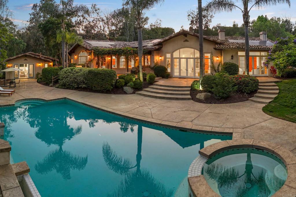 Designed for privacy and seclusion, this single-story Spanish-Mediterranean estate is set on over 2.5 fully gated acres on a corner lot in the highly sought-after west side of the Rancho Santa Fe Covenant. The main residence spans over 6,500 sq ft and features five en-suite bedrooms, a dedicated home office, a chef’s kitchen with Sub-Zero refrigerator and Viking range, soaring vaulted ceilings, and abundant natural light throughout. The detached guest house doubles as a pool house, offering brand-new waterproof flooring, a kitchenette, and a full bathroom—ideal for entertaining or extended stays. The expansive grounds present an incredible opportunity to add enhanced amenities such as a putting green, tennis court, or pickle ball court. Ideally located just minutes from the Rancho Santa Fe Golf Club, the Village, and the coast, this property offers a rare blend of timeless architecture, usable land, and exceptional convenience.
