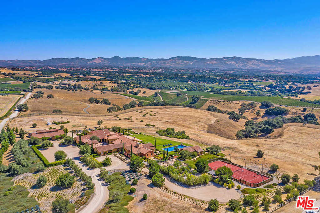 An escape from the bustle of city life, this Hacienda-style estate is situated on 18.8 picturesque acres in the Santa Ynez Valley. Surrounded by endless mountain and vineyard views, the 8-bedroom estate offers extraordinary privacy, space and amenities. Built in 2012, the residence exquisitely blends traditional design and modern sensibilities. Mission-style doors lead to open, airy interiors with 16, vaulted, beamed ceilings and expansive glass doors. The Spanish-tiled kitchen boasts premier appliances, a built-in pizza oven and walk-in pantry. The elegant master features a patio, water feature, Spanish tile shower and soaking tub, while a guest unit has its own entrance and sitting area. Amenities include a pool, Argentinian Gaucho grill, gym, vegetable garden, professional, all clay tennis court and a separate barn. A serene retreat surrounded by natural beauty, the estate is minutes from acclaimed schools, shopping, dining & wineries, and a 45-minute drive from Santa Barbara.