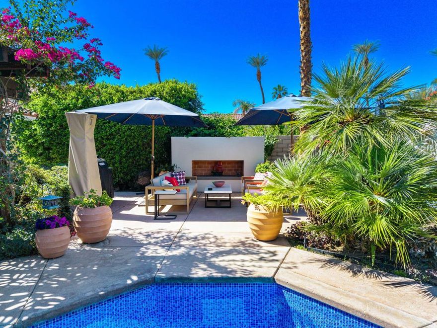 This beautifully designed 4-bedroom, 2-bath home offers 1,914 square feet of living space in the heart of Palm Desert in the gated community of Hovley Court. Blending modern comfort with resort-style luxury, the open and airy layout welcomes you with high ceilings, expansive windows, and a seamless flow between the living, dining, and kitchen areas.The spacious living room features a cozy tiled fireplace, vaulted ceilings with recessed lighting, and sliding glass doors that open to the lush outdoor patio, filling the space with natural light. The adjoining dining area continues the open-concept design, with neutral tile flooring that connects effortlessly to the kitchen and entertaining spaces.The chef's kitchen is both stylish and functional, showcasing custom wood cabinetry, sleek quartz countertops, and a large waterfall-edge island perfect for casual dining or meal prep. Stainless steel appliances, including a gas cooktop, built-in microwave and wine cooler, complete this modern culinary space.The primary bedroom suite is a serene retreat featuring vaulted ceilings, plush carpeting, and direct access to the backyard. The spa-inspired updated ensuite bathroom includes marble finishes, a freestanding soaking tub, a frameless glass shower with dual shower heads, and a custom double vanity. Just outside, a private outdoor shower enhances the resort-like experience.Two additional guest bedrooms offer comfort and versatility, while the fourth bedroom has been thoughtfully converted into a stylish TV room and home office with built-in cabinetry and a workspace nook--ideal for remote work or relaxation.Step outside to your own private paradise. The backyard is a stunning desert oasis with lush tropical and desert landscaping, a sparkling pool and a relaxing hot tub and a shaded pergola dining area perfect for entertaining. A cozy outdoor fireplace, misting system and shower complete the resort ambiance, offering the ultimate indoor-outdoor lifestyle.Additional features include 2020 5 ton Lennox AC, new water heater, new sliders, separate laundry room with newer washer and dryer, and a spacious three-car garage with mini-split AC.This home perfectly combines modern design, functionality, and resort-style living--an inviting sanctuary for both everyday comfort and effortless entertaining.