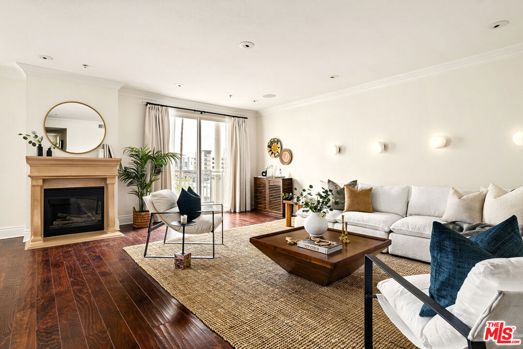 Unit 301 boasts an enviable layout, the most spacious of this charming building's six condo homes. Two sets of sliding glass doors frame the fireplace and open onto a pair of eastward-facing balconies that fill the open living-dining area with natural light. You can catch glimpses of the Hollywood skyline, including the Griffith Observatory, from your sofa, dining table, and private patio. The guest bedroom includes a built-in workspace and could easily double as your home office. The en-suite primary bedroom includes a generous walk-through closet that leads to a chic oversized bath with a free-standing soaking tub, new tile floors, new marble shower tile, a new shower, and new sink & light fixtures. If you run out of room in the primary closet, fret not: a custom shoe and accessories closet has been added to the end of the hallway to keep your finds well-organized. The guest bathroom has been shown an equal amount of style and care, with a remodeled step-in shower with marble tile and upgraded fixtures. Unit 301 has been extensively updated, including new limestone tile floors and quartz countertops in the kitchen, new hardware, fixtures, and fresh paint throughout, and an integrated sound system. Statement lights in the primary bedroom and dining area bring a bit of panache, but the designer pebble light sconces lining the living room walls help make this home feel truly unique. 1023 Wilcox Ave is located in the heart of the Hollywood Media District; this central location gives you quick and easy access to some of the best dining in the city, including Providence, Mother Wolf, and Rao's. It's also just down the street from Gold's Gym and movie nights at Hollywood Forever Cemetery. Melrose and Larchmont Village are close enough that you can leave your car at home in one of your two spaces in the gated, subterranean lot.