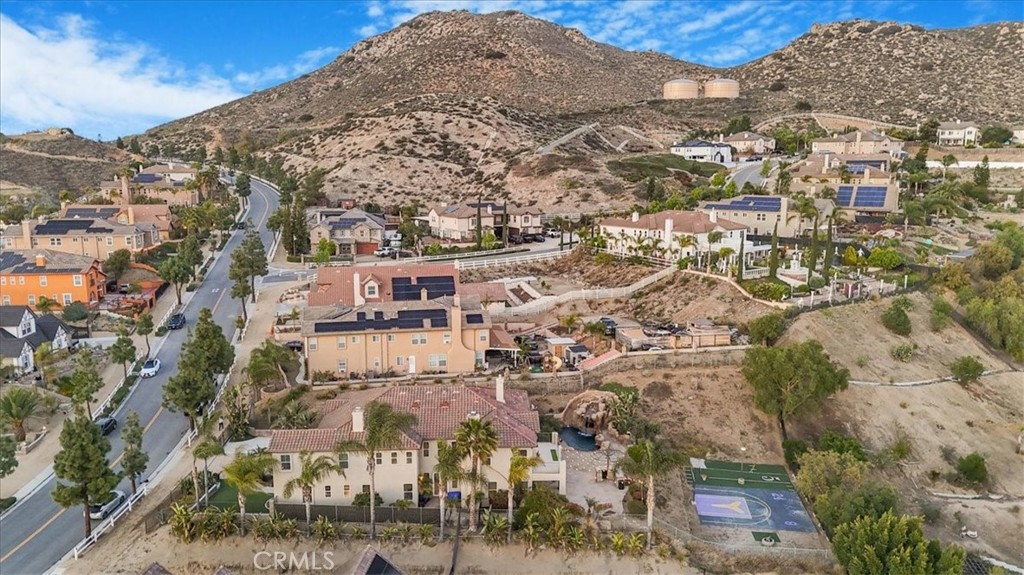 Welcome to Ridge Canyon Estates—one of Norco Hills’ most prestigious communities.
Perched near the top of the neighborhood, this custom-built estate offers sweeping views of the valley, mountains, and twinkling city lights. A gated driveway leads to your private, peaceful retreat.
Inside, soaring ceilings and a dramatic spiral staircase set an impressive tone. To the right, a private en-suite bedroom is ideal for guests or multi-generational living. To the left, a flexible room with its own across from the hallway bath that can serve as an office, gym, den, or additional bedroom.
The formal living room features a custom fireplace and French doors opening to a serene water fountain. Adjacent, the formal dining room—with its wine room—is perfect for entertaining, flowing seamlessly into the living area for elegant gatherings.
Toward the back, The Great Room opens to the gourmet kitchen and offers built-in cabinetry, a cozy fireplace, and stunning backyard views. The chef’s kitchen features stainless steel Viking appliances, a large center island, and a casual dining area overlooking the pool, spa, and dramatic cityscape—making it the heart of the home.
Upstairs, a spacious loft offers endless possibilities. The massive primary suite is a true retreat, complete with fireplace, sitting area, and private balcony to take in the breathtaking views. The spa-like primary bath features a dual-sided shower, Jacuzzi soaking tub, dual vanities, the best part unlike other homes in the area - private laundry, walk-in closets, and separate toilet room.
Three additional bedrooms complete the upper level—two sharing a Jack & Jill bath with private vanities, and one with its own full bath en-suite. Built-in cabinetry and a custom home theater with 5.1 surround sound finish off the second floor.
Step outside to a resort-style backyard, perfect for relaxation and entertainment. Enjoy the custom grotto, pool and spa with slide and waterfall, integrated lighting, built-in BBQ island with kitchenette with refrigerator, TV setup, running electrical and water, and two fire pits. The lower lot includes a half-court basketball area with spotlight and space to add equestrian facilities if desired.