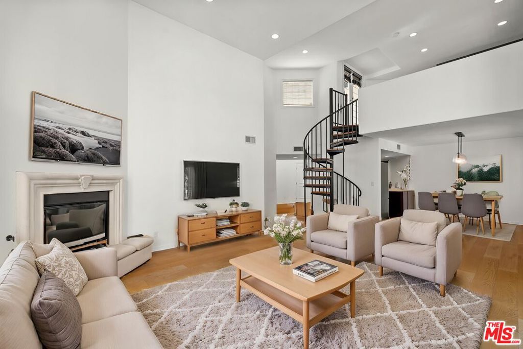Welcome to this beautifully designed, light-filled penthouse that blends modern style with functionality. Featuring 3 bedrooms, 3.5 bathrooms, and 1,835 SF of living space, this sophisticated unit boasts soaring 14-foot ceilings, oversized windows, recessed lighting, and a cozy decorative fireplace. The main floor includes two spacious bedrooms, with an oversized primary bedroom with luxurious bathroom. An updated kitchen with top of the line stainless steel appliances opens to the dining area and offers ample storage and counter space. A spiral staircase leads to a flexible loft-style third bedroom, complete with custom built-ins and its own en-suite bath ideal as a home office or guest suite. French doors open to a private rooftop deck, a true oasis featuring a grill, overhead heater, and Moroccan-inspired seating area, perfect for entertaining. Additional highlights include in-unit stacked laundry and two-car tandem parking. Just one block from Beverly Hills and 3rd Street, this prime location puts you steps from trendy cafes, boutiques, and moments from Cedars-Sinai.