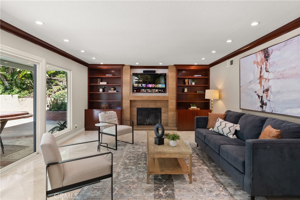 This beautifully upgraded Estate II District home, built by S&S Homes, is located in the sought-after East Lake Village community of Yorba Linda. With 4 bedrooms, 3 bathrooms, and a large bonus room (or optional 5th bedroom), this spacious home offers approximately 3,850 sq ft of thoughtfully designed living space that blends comfort, elegance, and functionality. Step inside to find soaring ceilings, travertine flooring, and a formal living room with fireplace and tall windows. The adjoining formal dining room features crown molding and a built-in wine fridge, creating the perfect space for entertaining. At the heart of the home is a chef’s kitchen with granite counters, wood cabinetry, center island seating, and a WOLF 6-burner stove with pot filler. The kitchen opens to a welcoming family room with fireplace and oversized sliding glass door leading to the backyard. A downstairs bedroom with marble floors and direct backyard access is ideal for guests or a home office. A full bathroom and dedicated laundry room complete the main level. Upstairs, the primary suite is a true retreat—offering a fireplace, walk-in closet, newer windows, and a private balcony. The ensuite bath includes dual vanities, a walk-in shower, and ample storage. Two additional bedrooms upstairs (one with vaulted ceilings) share a full hall bath with granite counters and travertine flooring. A spacious bonus room with vaulted ceilings, the home’s fourth fireplace, and a wet bar adds flexibility for a media room, lounge, or game room. Enjoy a private backyard oasis featuring an Alumawood patio cover with fan, sparkling pool and spa, lush landscaping, a lemon tree, and plenty of space for outdoor living. Additional upgrades include a newer roof and electrical panel. East Lake Village offers resort-style amenities including pools, clubhouse, tennis, gym, lake trails, and more—all within award-winning PYLUSD.