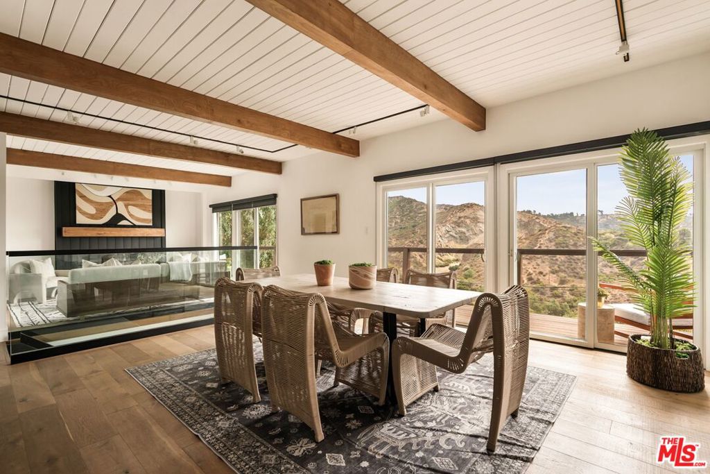 Tucked into the coveted Hollywood Hills, just below the iconic Hollywood Sign, 2832 Hollyridge Drive is a private hillside sanctuary designed to blend modern elegance with California's quintessential indoor-outdoor lifestyle. This residence showcases sun-drenched interiors and sweeping panoramas of Griffith Observatory, Downtown Los Angeles, and the surrounding canyons. Behind a gated entry, the home unfolds into airy, open living spaces framed by walls of glass and dramatic sight-lines. The main level is anchored by a bright and inviting living and dining area featuring wide-plank flooring, shiplap accents, and a striking architectural steel and glass staircase. The chef's kitchen is equipped with custom shaker cabinetry, quartz countertops, and premium stainless steel appliances, offering seamless access to an expansive wraparound deck--perfect for stylish entertaining or relaxed al fresco dining. The home's four bedrooms are designed as private retreats, each capturing tranquil hillside vistas. The primary suite is a true haven, featuring a spa-inspired bathroom with dual vanities, designer finishes, and a glass-enclosed shower. A dedicated workout studio offers the convenience of wellness at home, while multiple balconies and generous decks extend the living experience outdoors--providing idyllic spaces for lounging, entertaining, and savoring golden sunsets over the city skyline. Set on a peaceful ridge-line, this residence offers exceptional privacy along with a two-car garage for secure parking and storage, all just moments from Franklin Village, Beachwood Canyon, and many hiking trails. With thoughtful upgrades, timeless design, and an emphasis on natural light and breathtaking views, 2832 Hollyridge Drive stands as a sophisticated modern sanctuary in one of Los Angeles' most legendary neighborhoods.