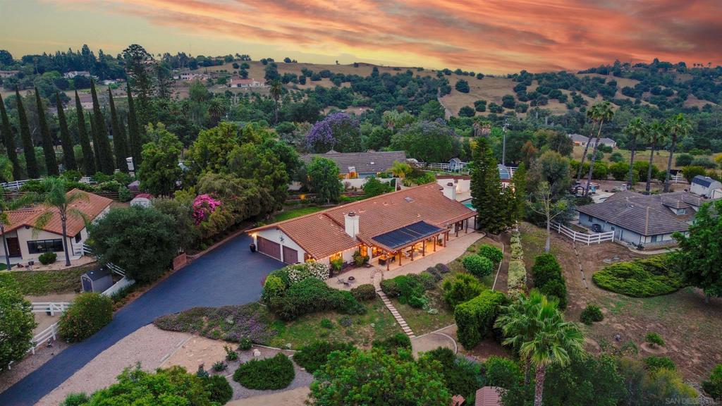 Welcome to 1036 Capra Way, an exquisite single-level luxury estate offering 4 bedrooms, 3 bathrooms, and 3,021 sq. ft. of refined living space on 1.3 private, gated acres. A long, olive tree–lined driveway creates an elegant arrival, leading to a striking stained double-door entry with iron accents. Inside, soaring vaulted ceilings with stained beams and expansive windows and glass doors fill the home with natural light, creating a seamless connection to the outdoors. Thoughtful architectural details include solid-core interior doors, wide baseboards, and custom louvered closet doors, showcasing craftsmanship at every turn. The kitchen provides abundant pantry storage, combining everyday function with timeless design. The outdoor spaces are truly resort-caliber, featuring a large pool and spa, expansive covered patio, and multiple entertaining areas surrounded by lush landscaping. The grounds include ten varieties of mature fruit trees, raised vegetable gardens, and a Pétanque court, offering both beauty and recreation. The finished garage is equally impressive, with a workbench, custom cabinetry, utility sink, and attic storage with drop-down ladder. A flexible hobby room with separate entrance provides additional space for guests, a studio, or private office. Blending elegance, privacy, and functionality, 1036 Capra Way embodies California living at its finest—a rare retreat designed for both everyday comfort and sophisticated entertaining.